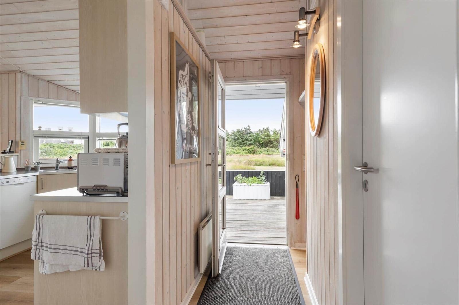 Küche mit Blick auf Terrasse und Garten. Holzwände und Fenster mit Blick.