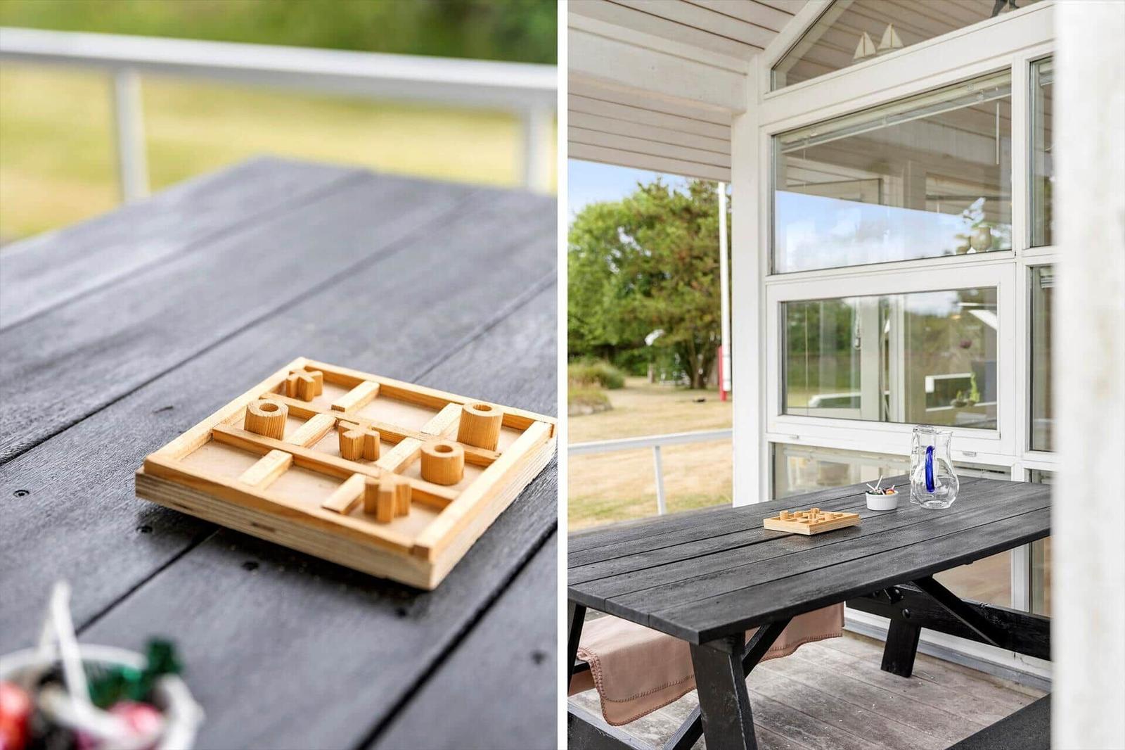 Holzspiel auf dunklem Tisch auf Terrasse mit Blick auf Garten und Haus.