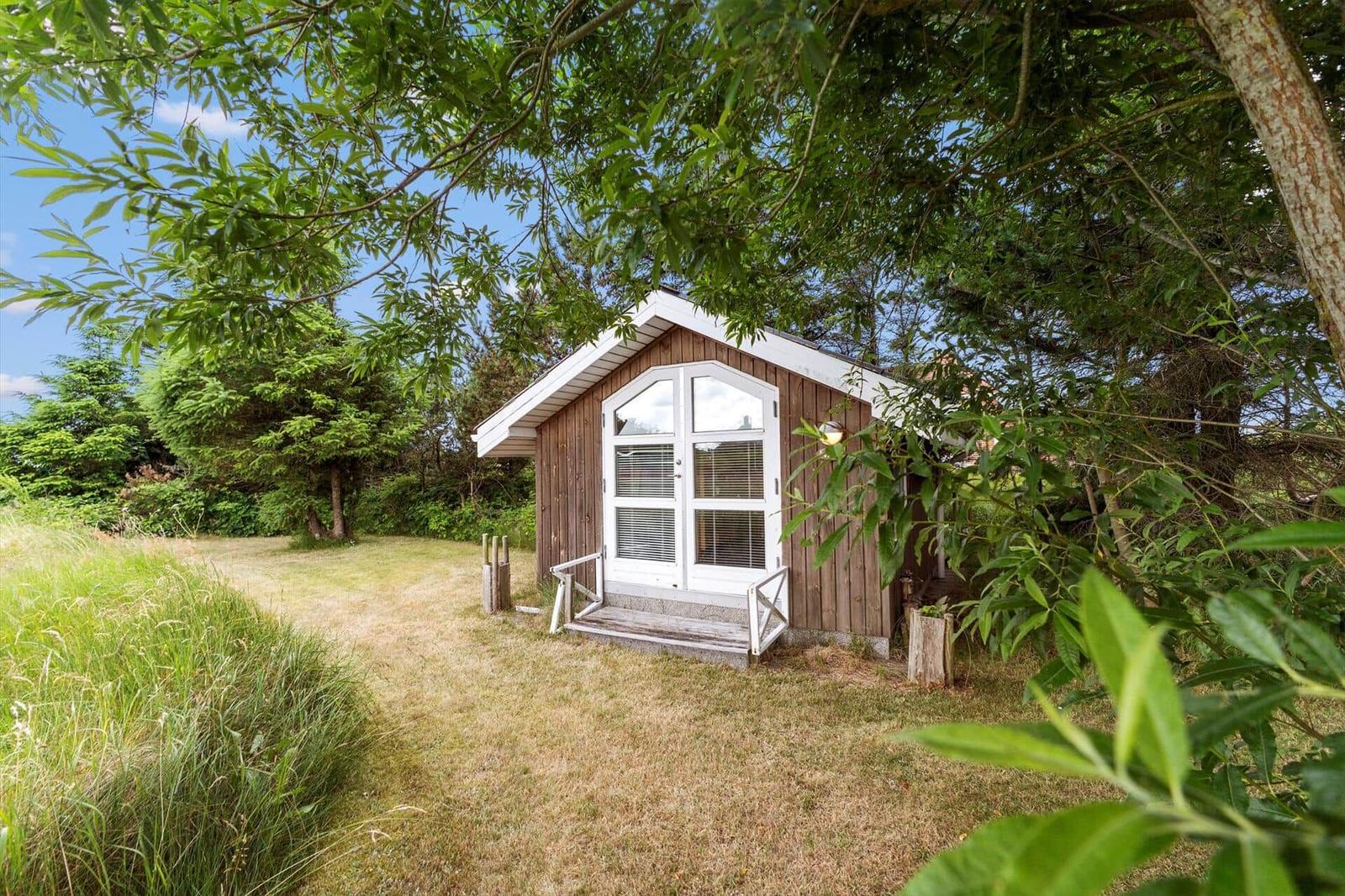 Holzhütte mit weißer Tür und Fenster im Grünen