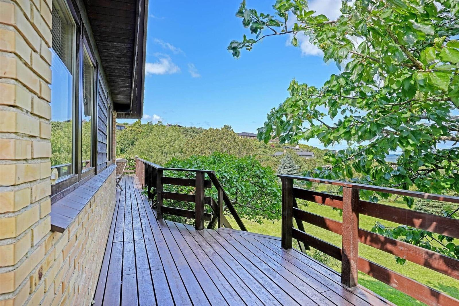 Wooden deck with view of green landscape and blue sky.