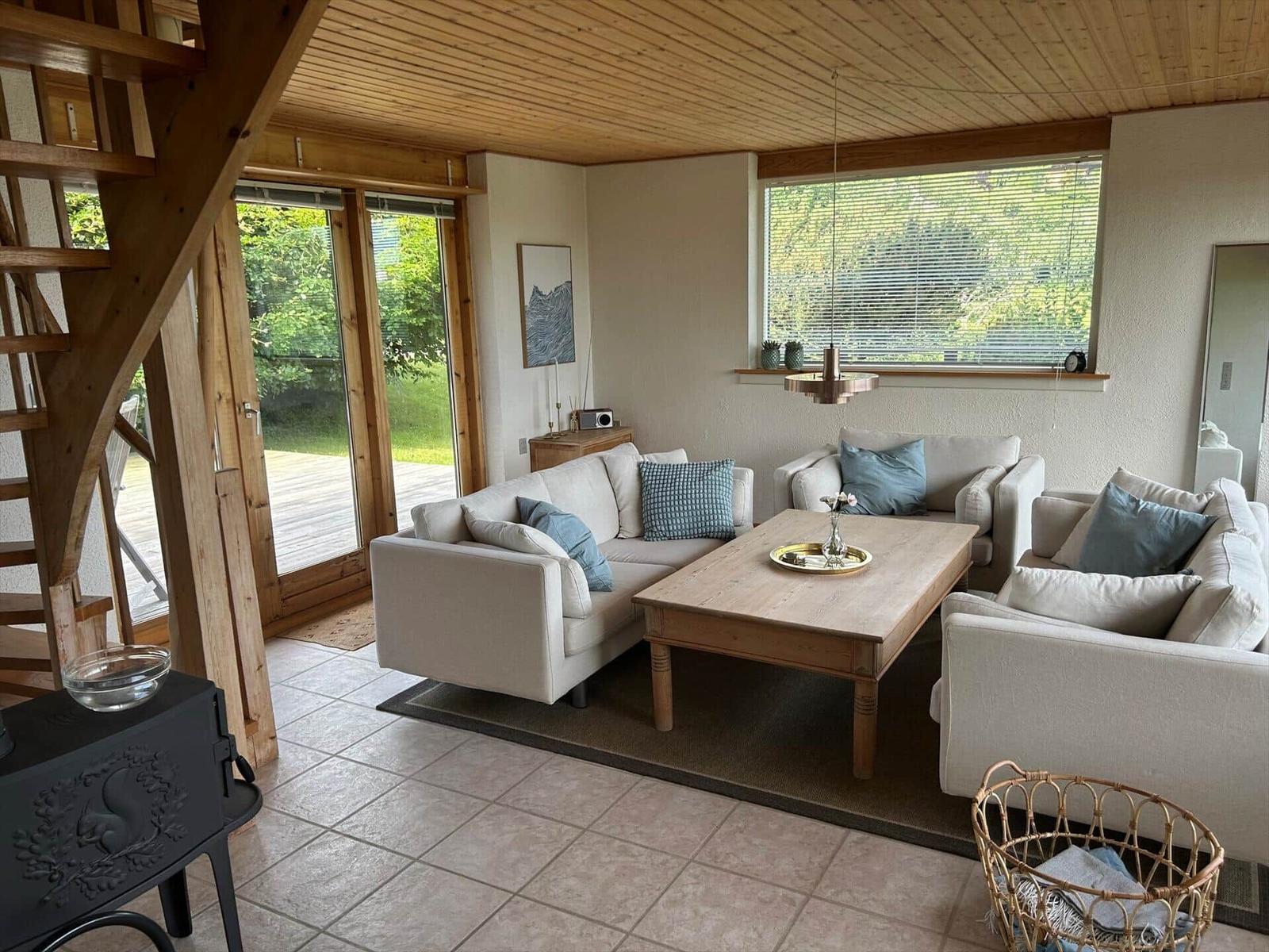 Living room with sofa, table, and windows. Wooden ceiling and terrace door.