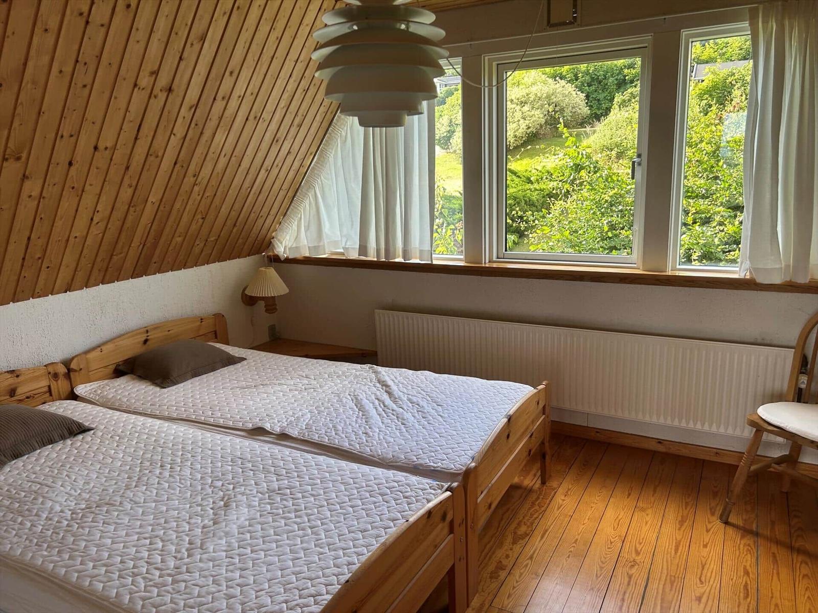 Bedroom with wooden floor, double bed, and view of green landscape.