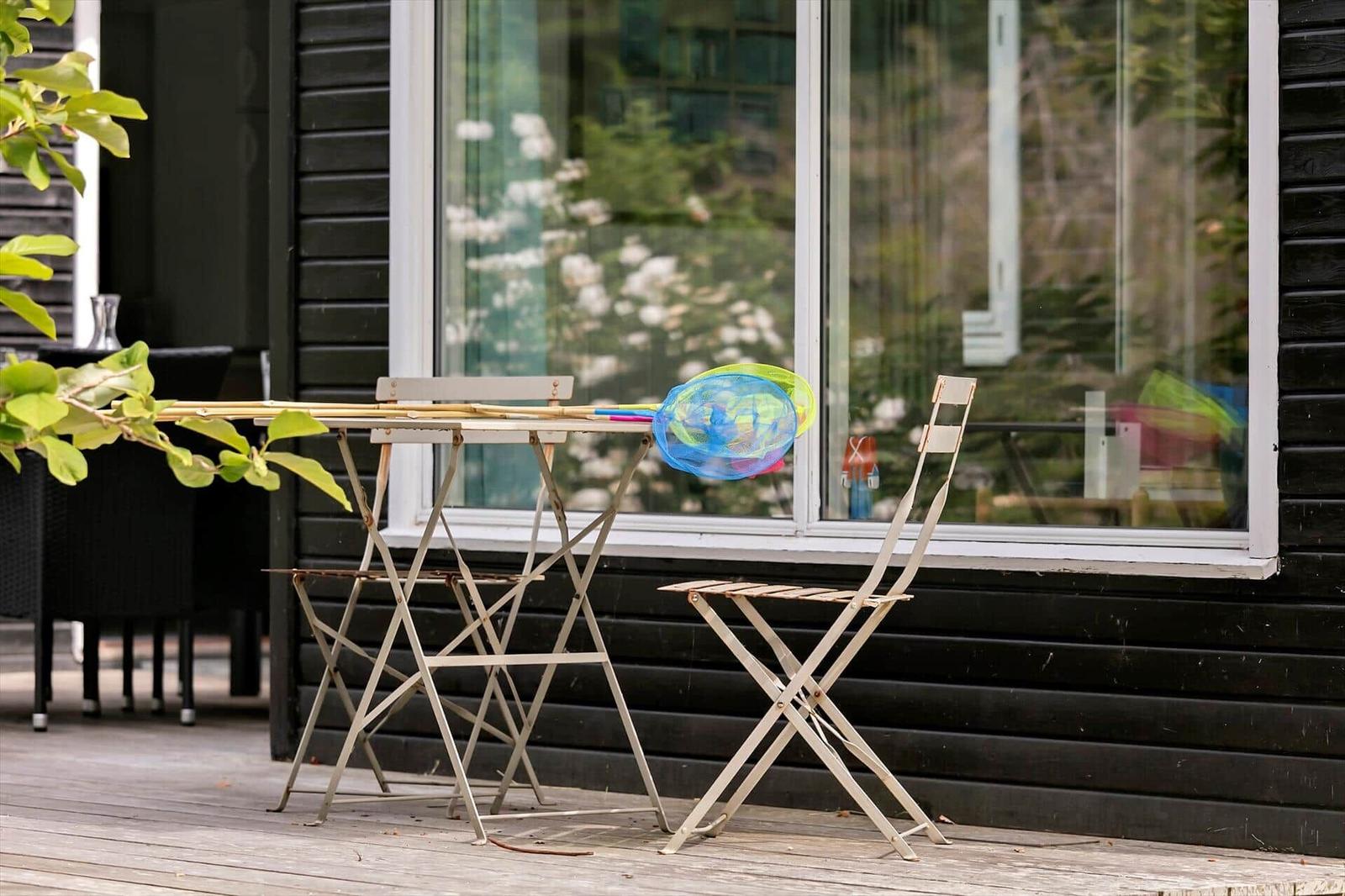 Outdoor area with table and chairs, beside a net and a stick.