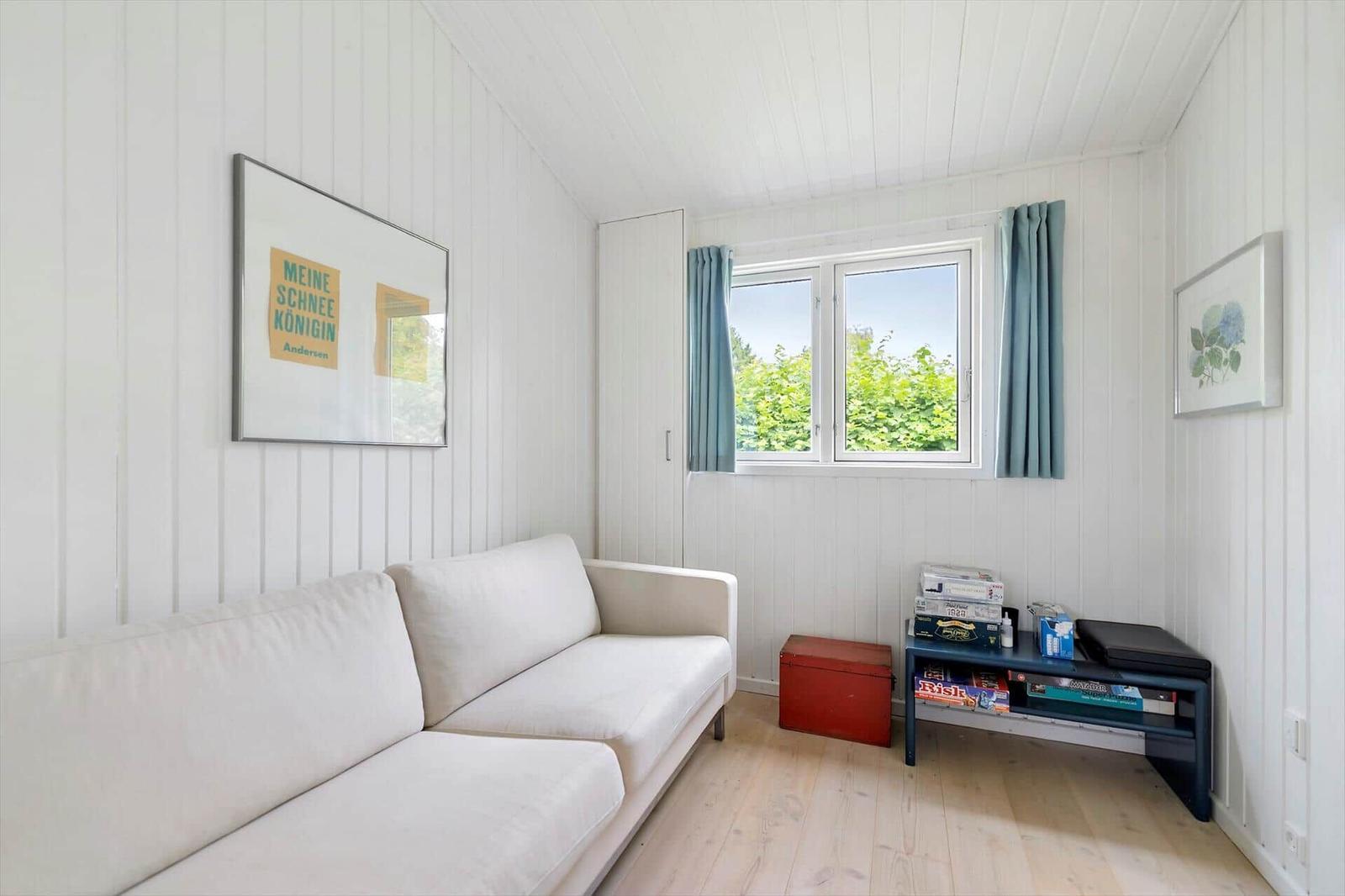 Living room with white sofa, window with blue curtains, and wooden floor.