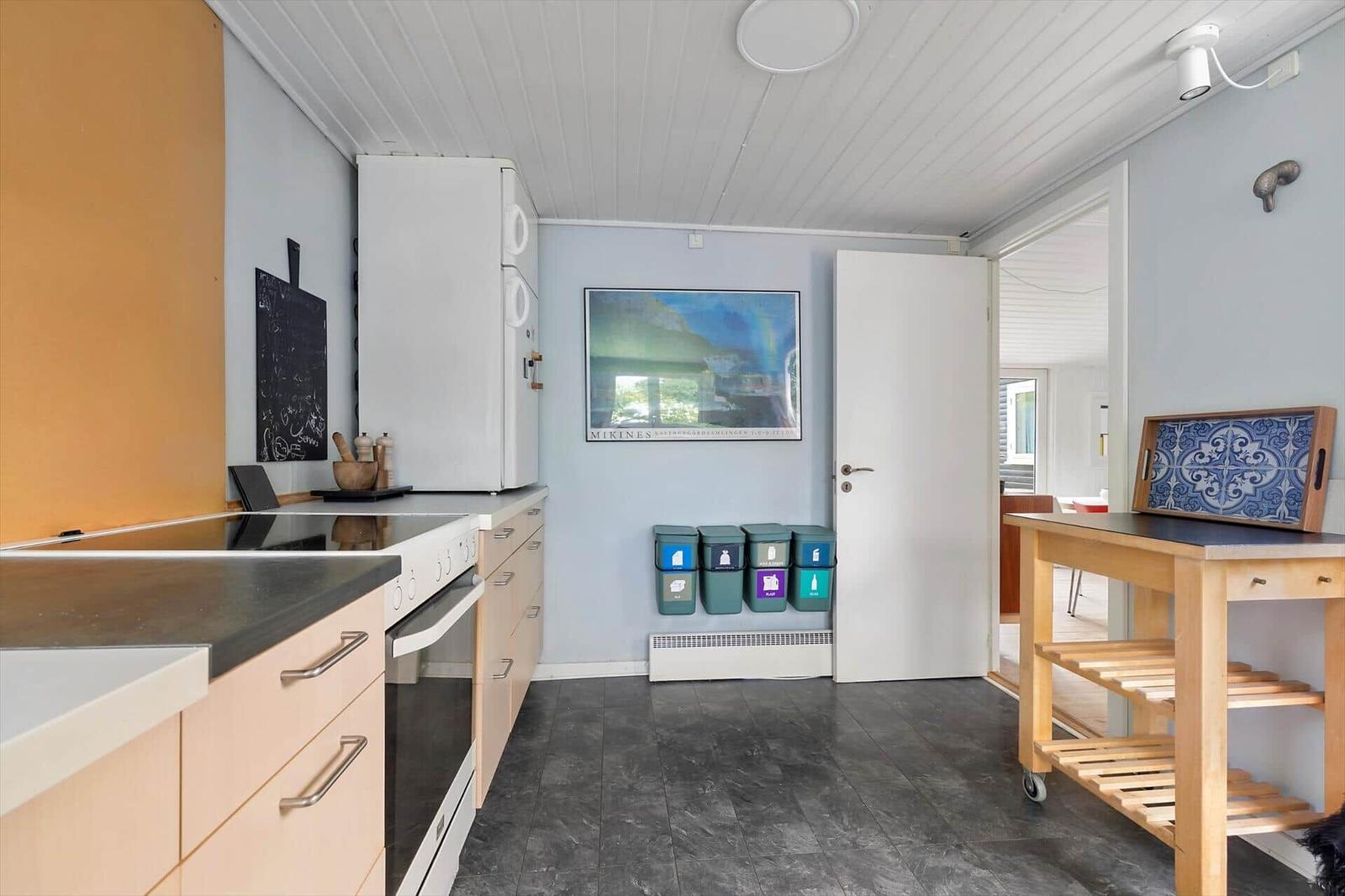 Kitchen with refrigerator, worktop, and waste sorting system.