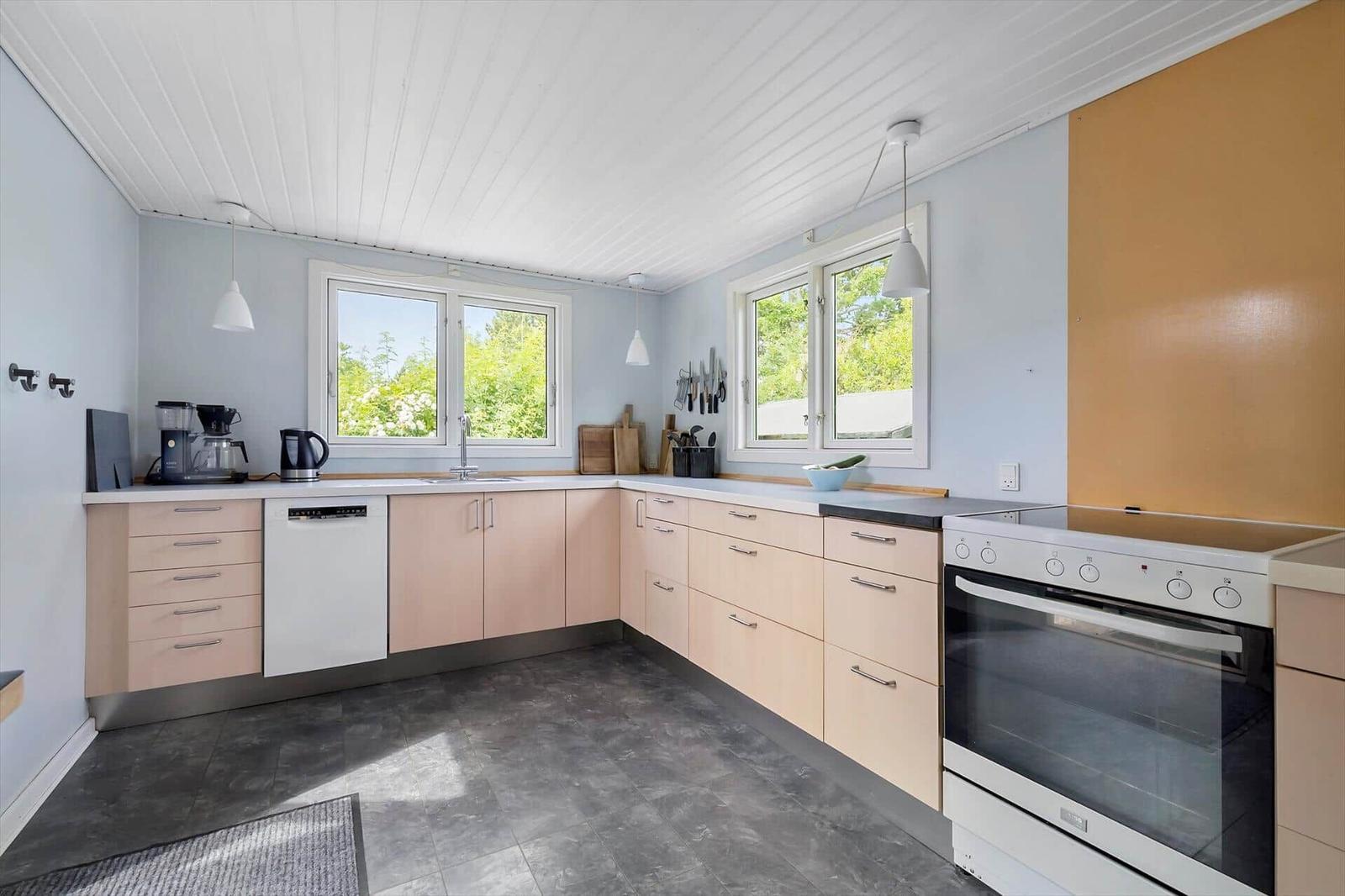 Kitchen with light cabinets, windows, and modern equipment.