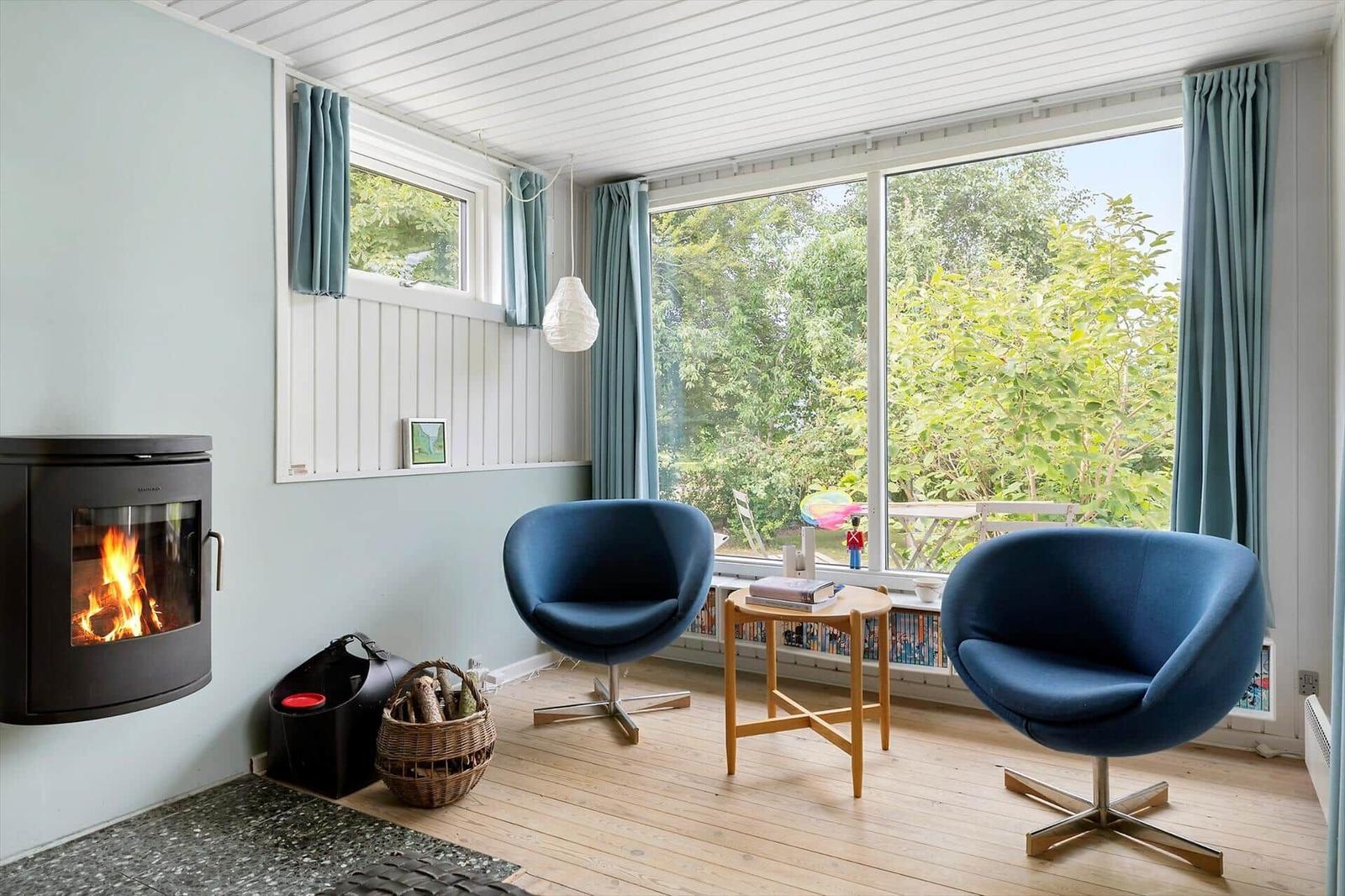 Room with fireplace, two blue chairs, and large window with view.