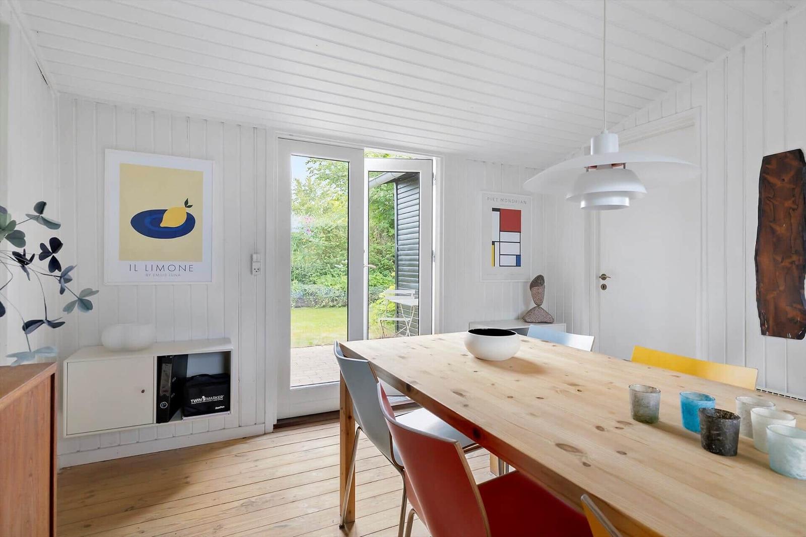 Dining room with wooden table, chairs, and window to the garden.