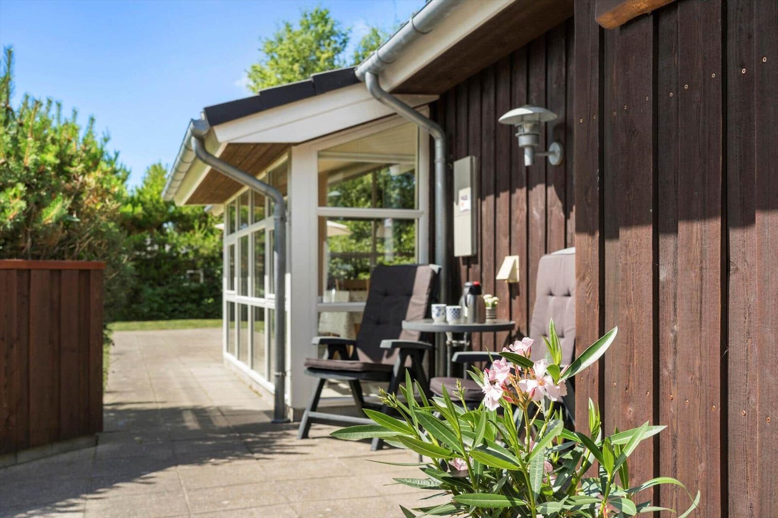 Terrasse mit Sitzgelegenheit und Blumen vor einem Holzhaus.
