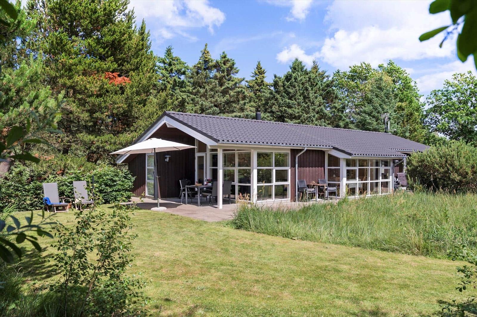 Ein Haus mit Terrasse, Garten und Sitzgelegenheiten unter freiem Himmel.