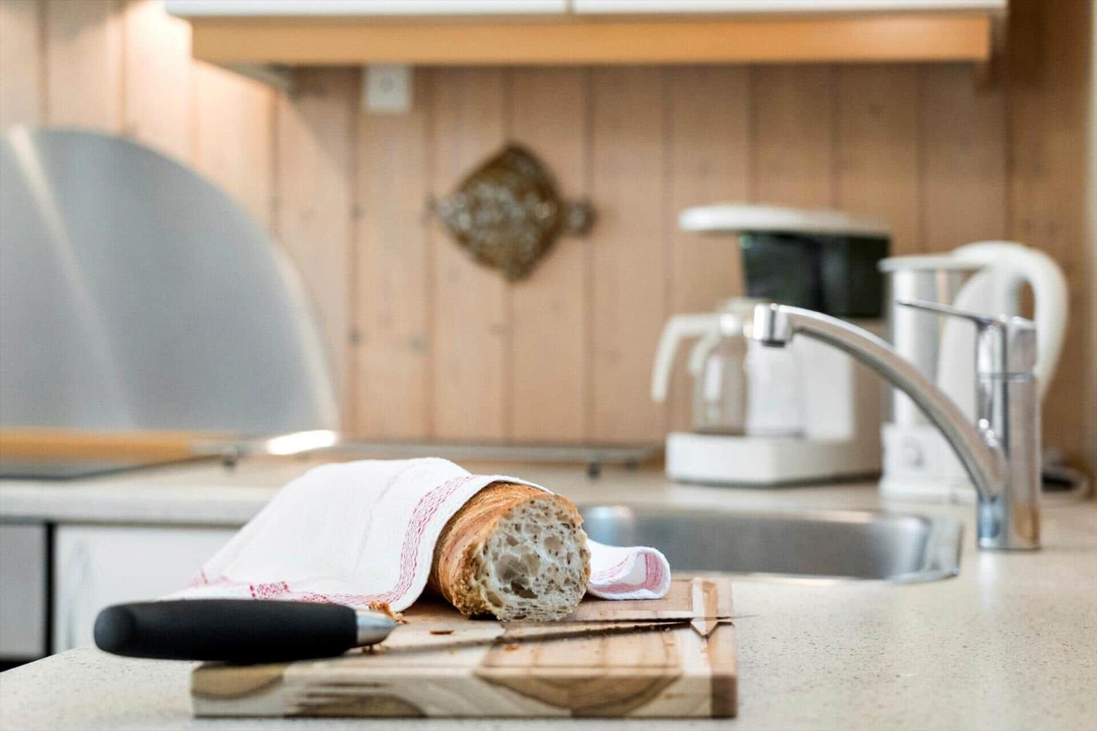 Ein frisch gebackenes Brot liegt auf einem Holzbrett in der Küche.