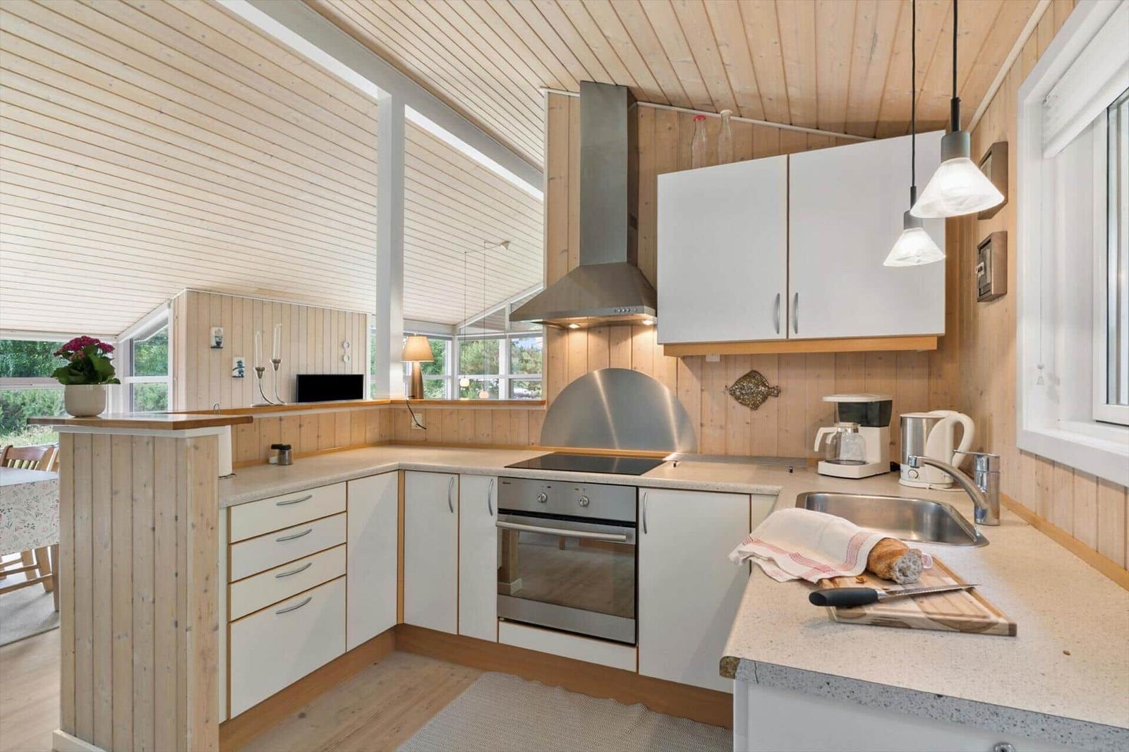 Küche mit Holzwand, weißen Schränken und Edelstahlherd.