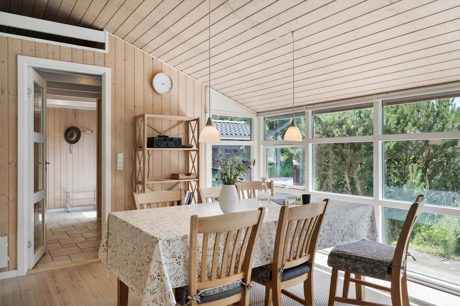 Esszimmer mit Holzwand, Tisch mit Stühlen und großem Fensterblick.