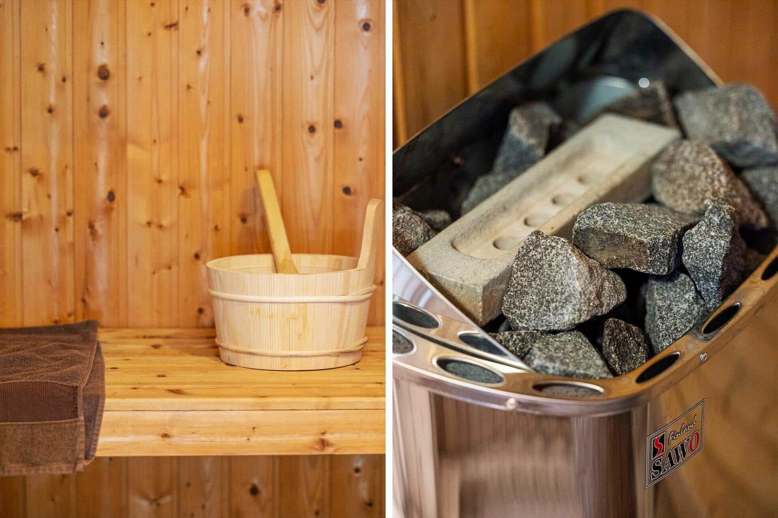 Sauna mit Holzbank, Badekörbchen und Steinofen mit heißen Steinen.