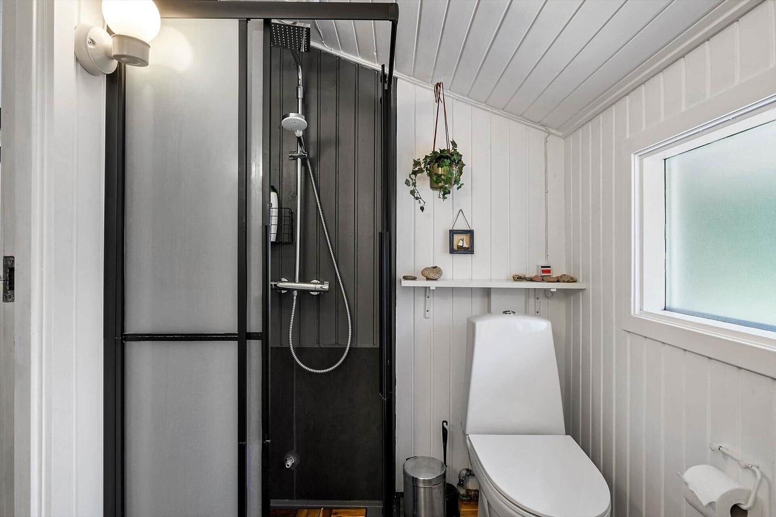 Dusche mit Duschbrause, Toilette und Fenster mit Milchglas