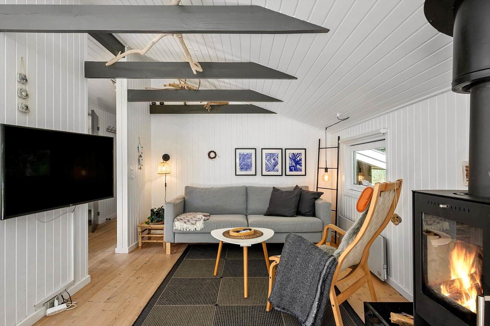 Wohnzimmer mit Sofa, Kamin und Fernseher an der Wand.