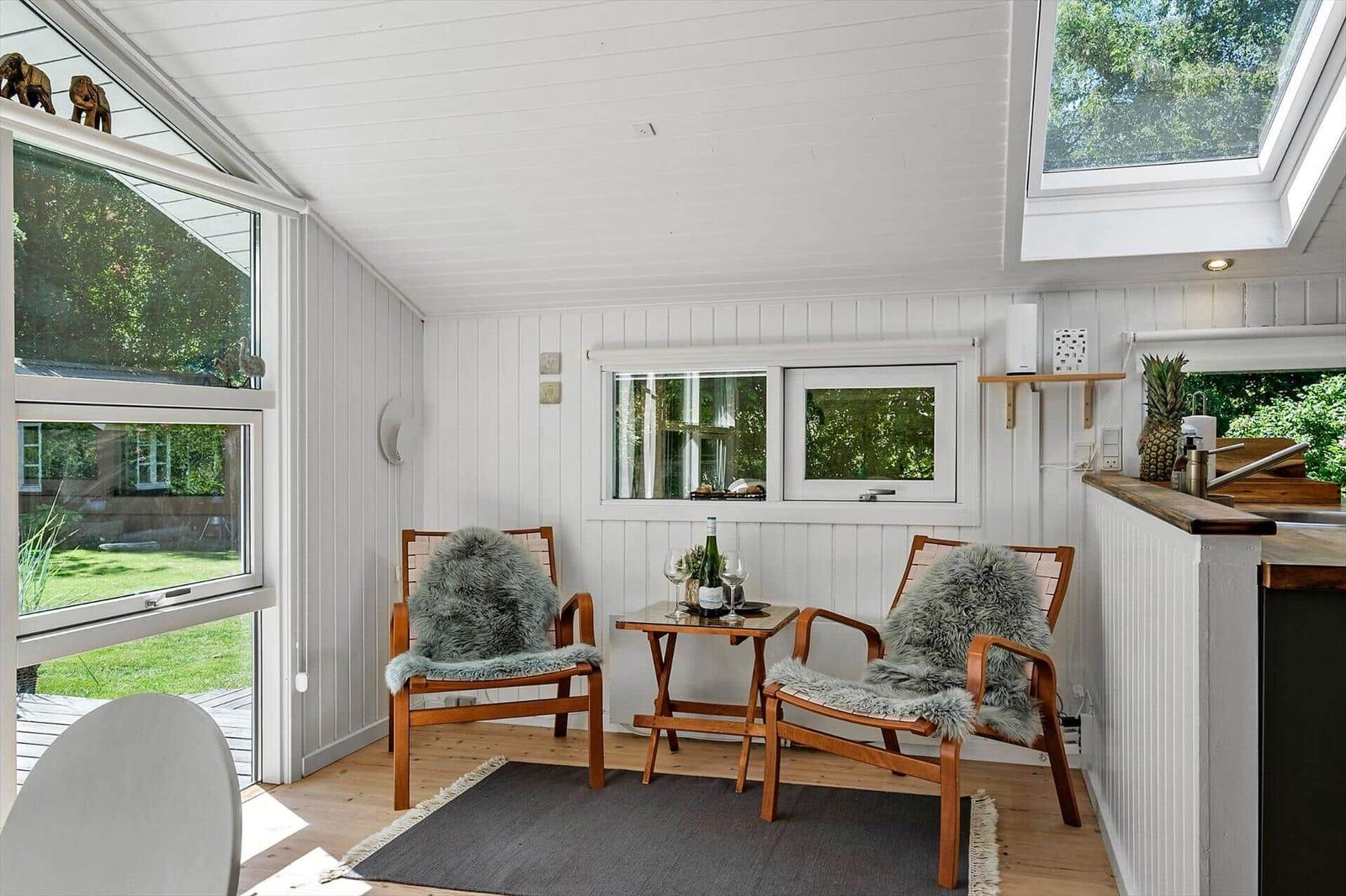 Zwei Stühle mit Felldecken stehen um einen Tisch herum. Fenster und Dachfenster bieten viel Licht.