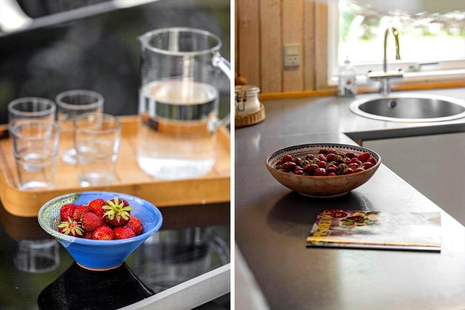 Küchenbereich mit Steinwaschbecken und Schale voller Erdbeeren.