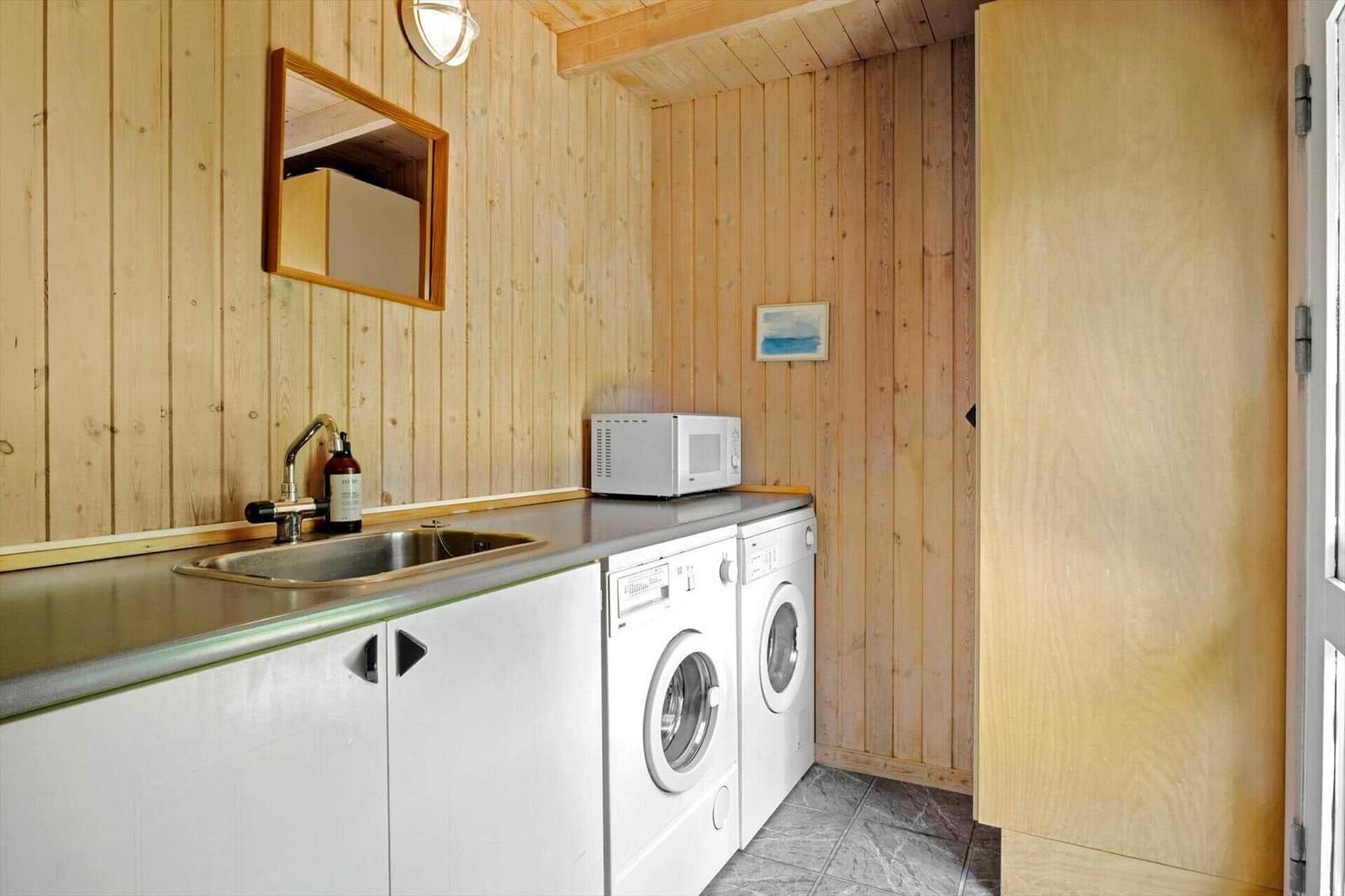 Küchenbereich mit Spüle, Mikrowelle und Waschmaschine in Holzwandung.