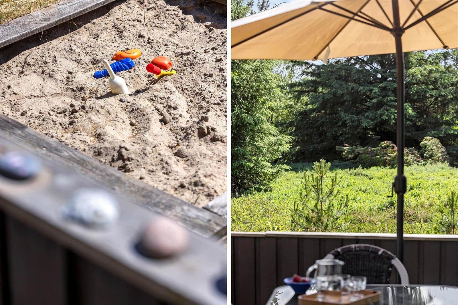 Spielplatz mit Sand und bunten Kinderspielzeugen. Terrasse mit Sonnenschutz und Blick auf grüne Wiesen.