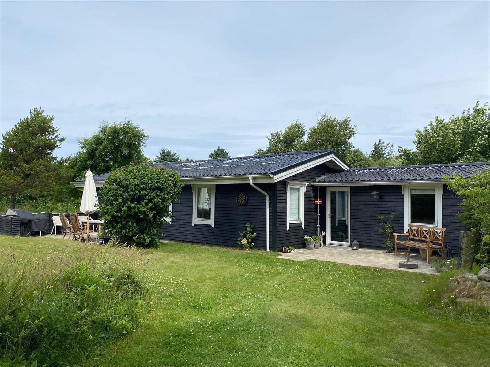 Schwarzes Haus mit Garten, Terrasse und Gartenmöbeln.