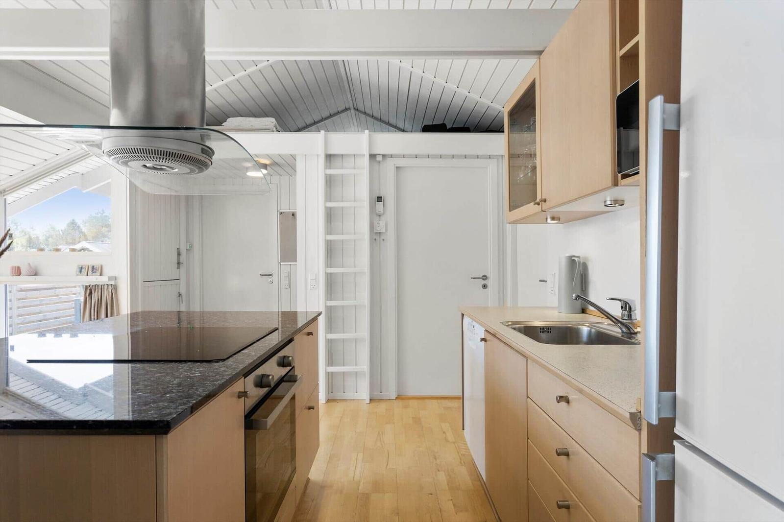Küche mit Holzschrank, Spüle, Herd und Dunstabzug.