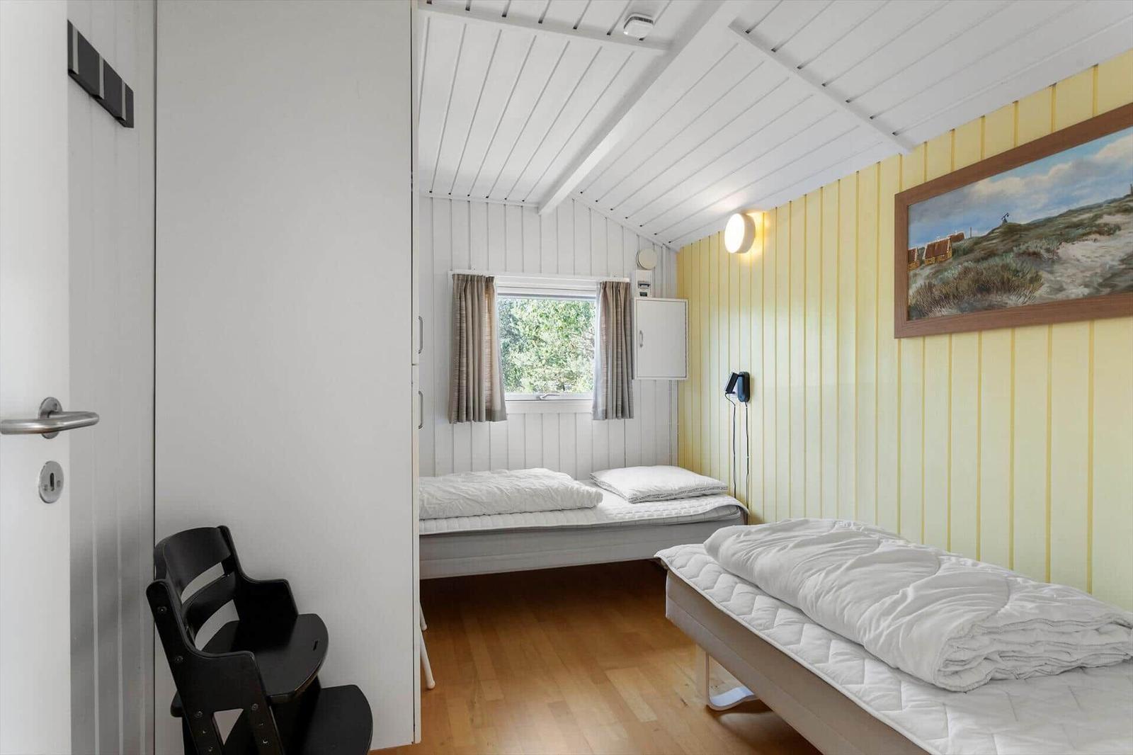 Zimmer mit zwei Betten, Fenster, Wandbild und Holzboden.