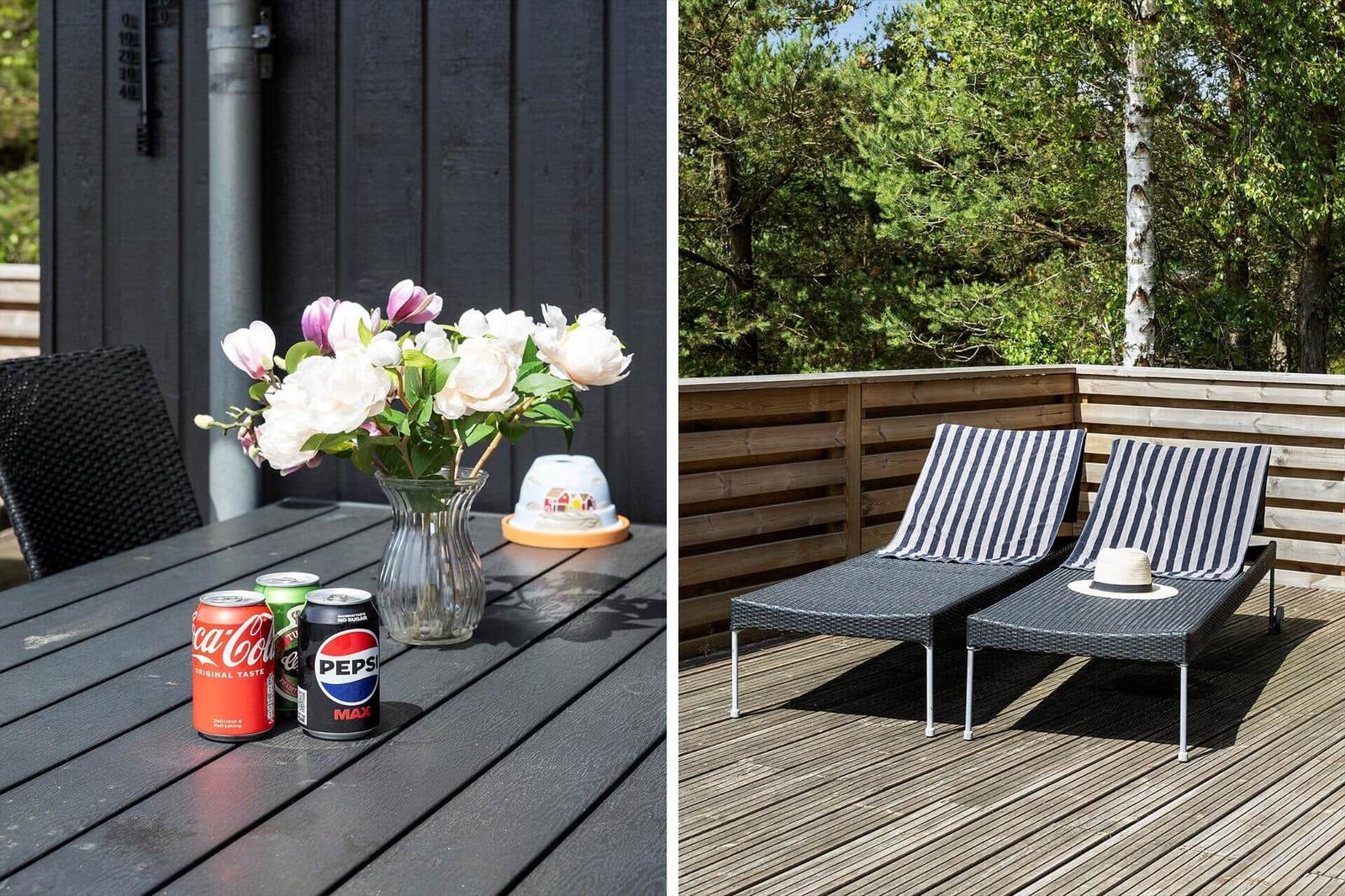 Terrasse mit Tisch, Blumen und Getränken. Liegestühle mit Streifenhandtüchern und Blick in den Wald.