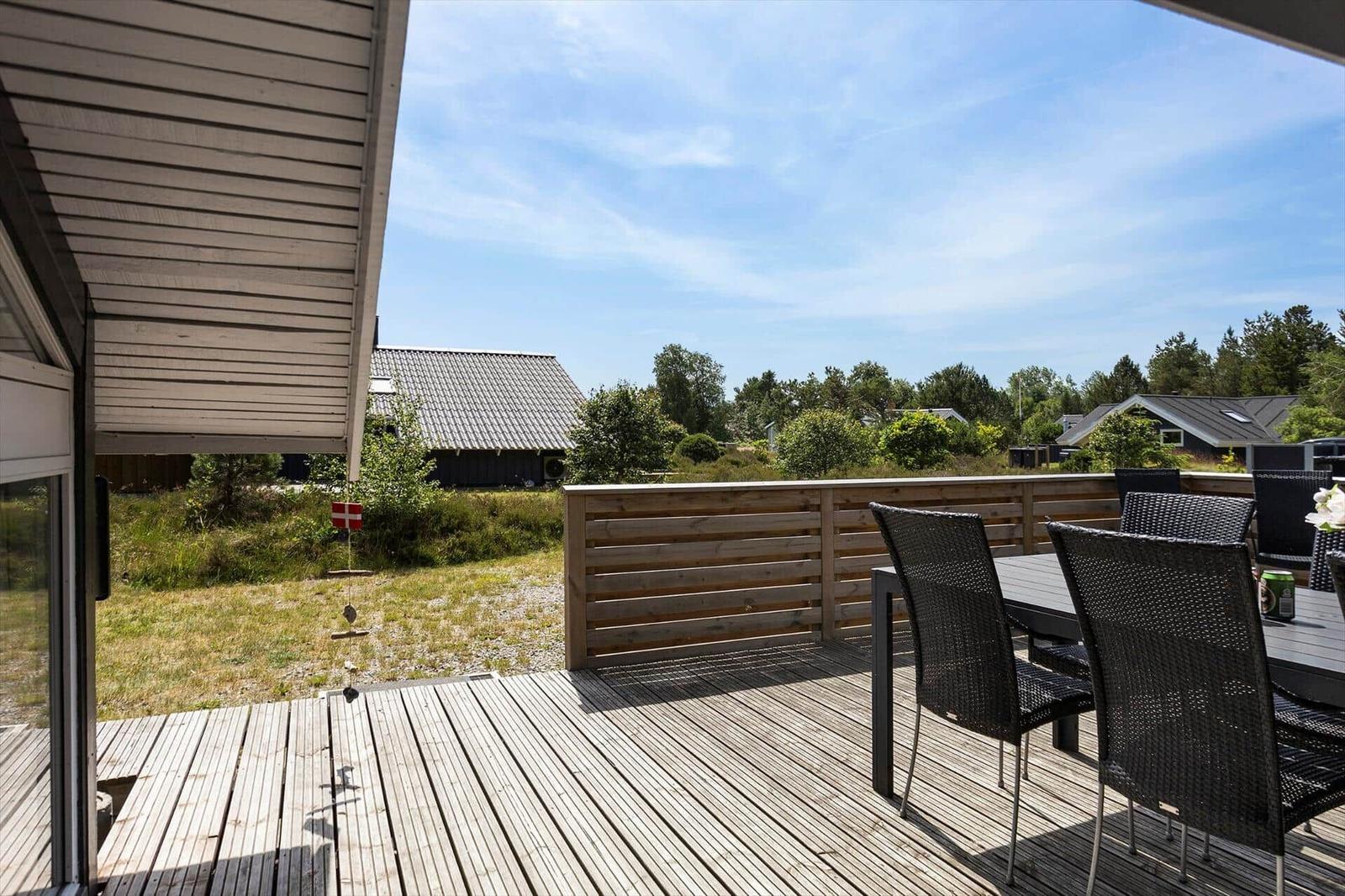 Terrasse mit Tisch und Stühlen, Blick auf Grünflächen und Häuser