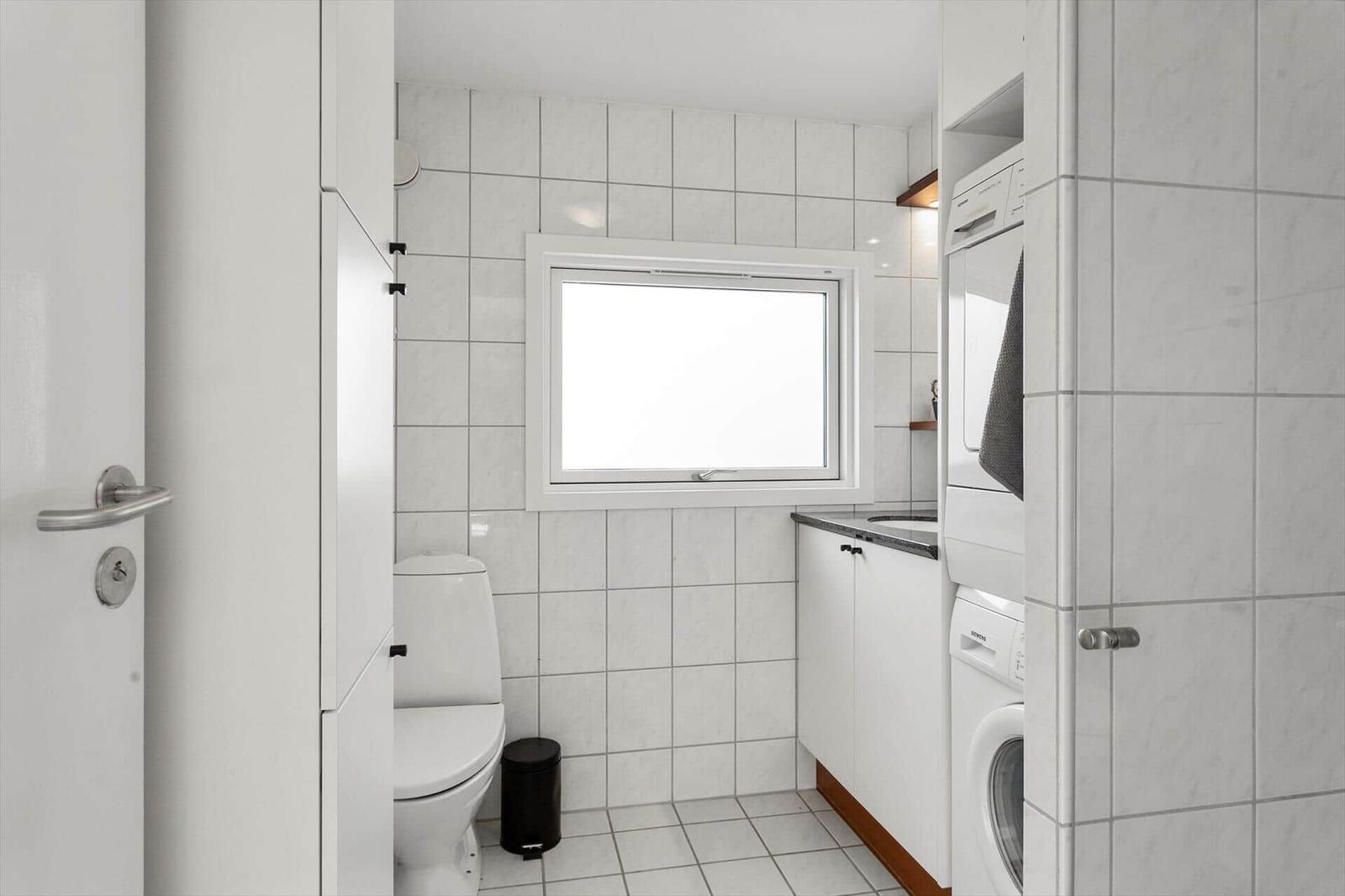 Badezimmer mit Toilette, Waschmaschine und Fenster