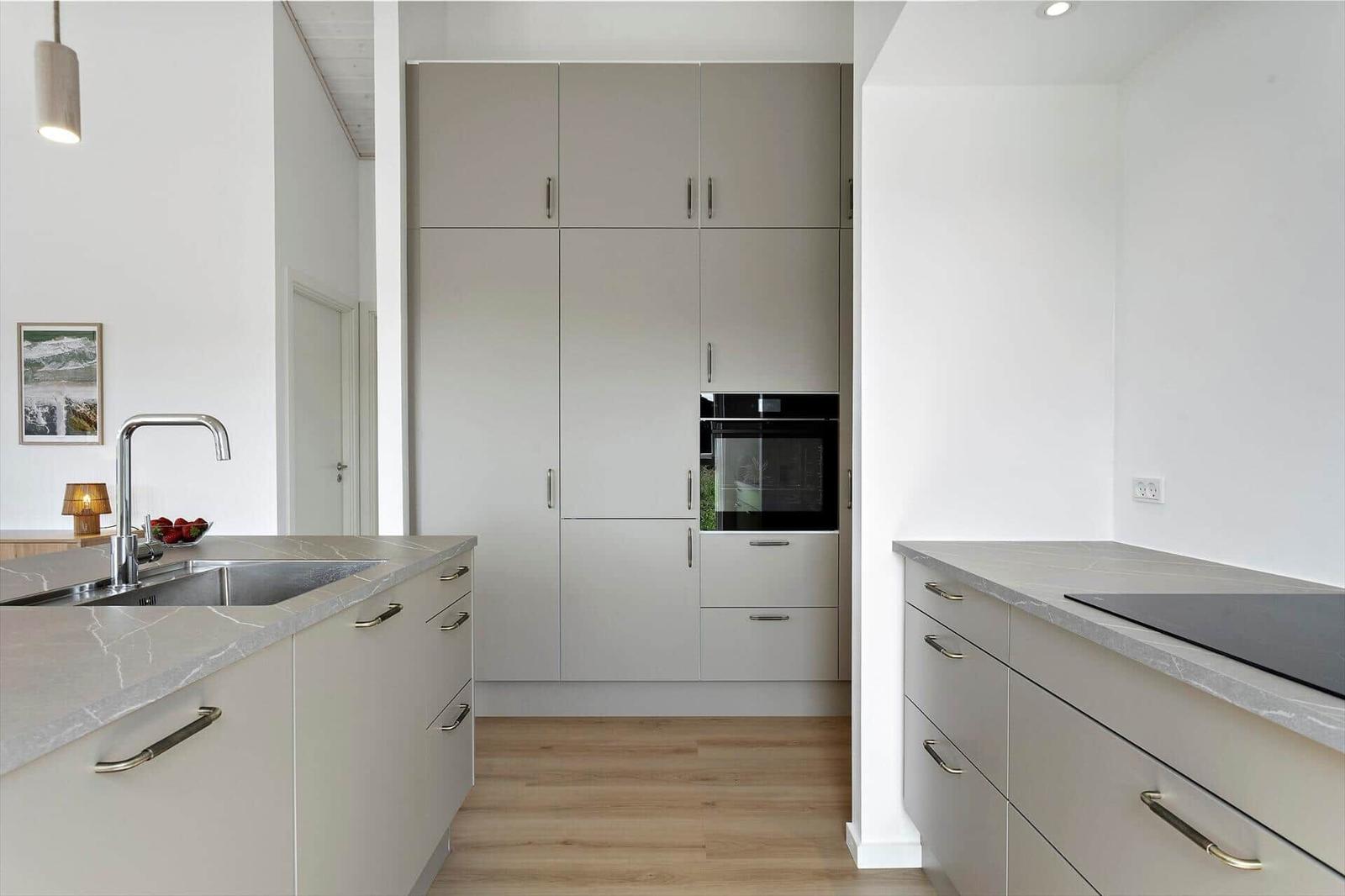 Moderne Küche mit hellen Schränken, Edelstahlspüle und integriertem Backofen.