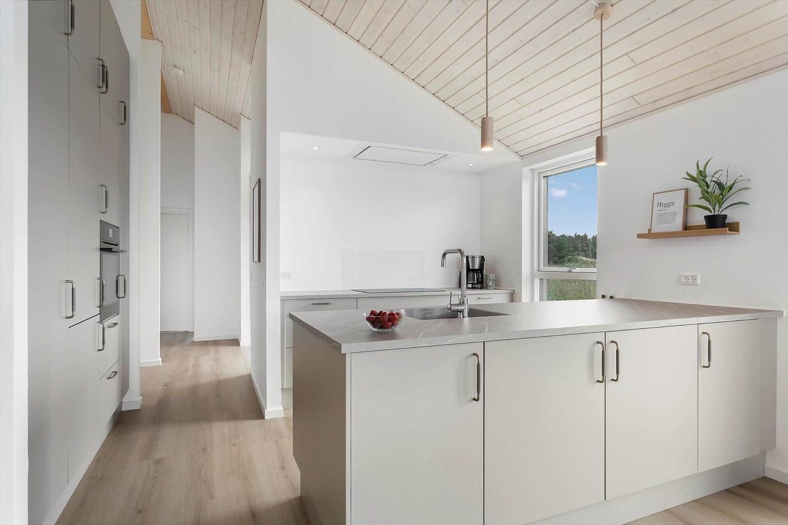 Moderne Küche mit Kücheninsel, Fenster und weißen Schränken.