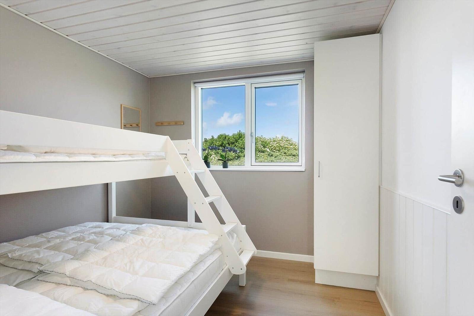 Ein Schlafzimmer mit Doppelstockbett, Fenster und Schrank.