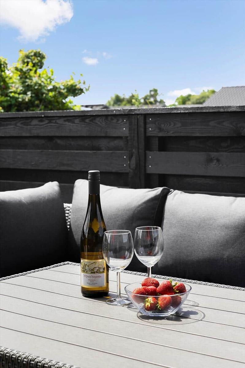 Auf der Terrasse steht ein Tisch mit Wein, Gläsern und einer Schale Erdbeeren.