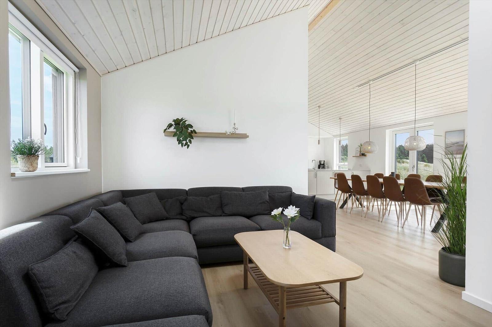 Wohn- und Essbereich mit grauem Sofa, Holztisch und Lichtdurchflutung.