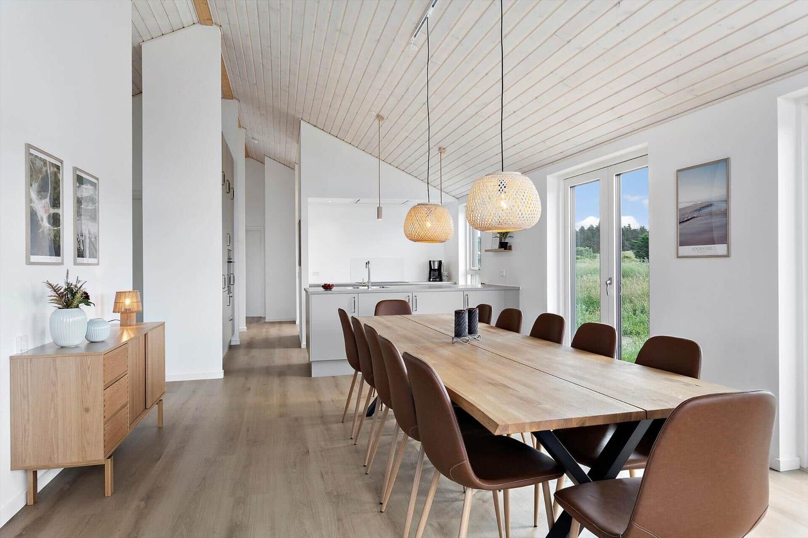 Esszimmer mit Holztisch, braunen Stühlen und Fenster zur Landschaft.