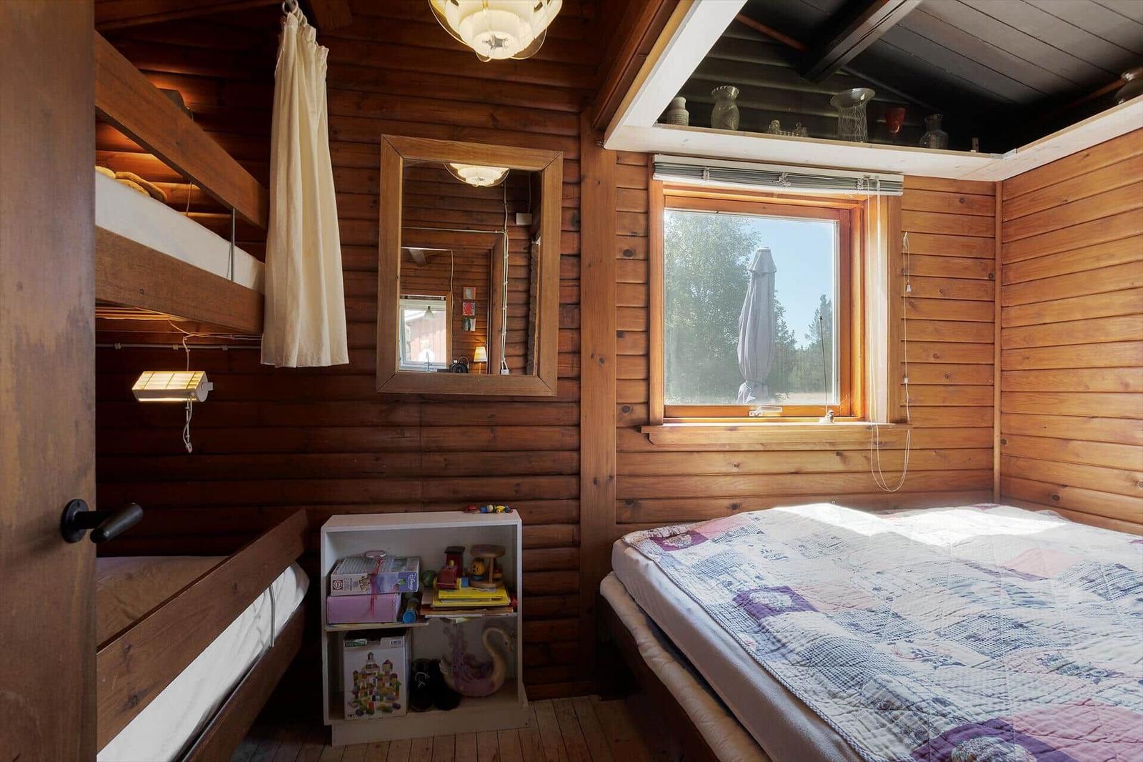 Zimmer mit Holzwand, Doppelbett, Schlafcouch und Fenster mit Blick.