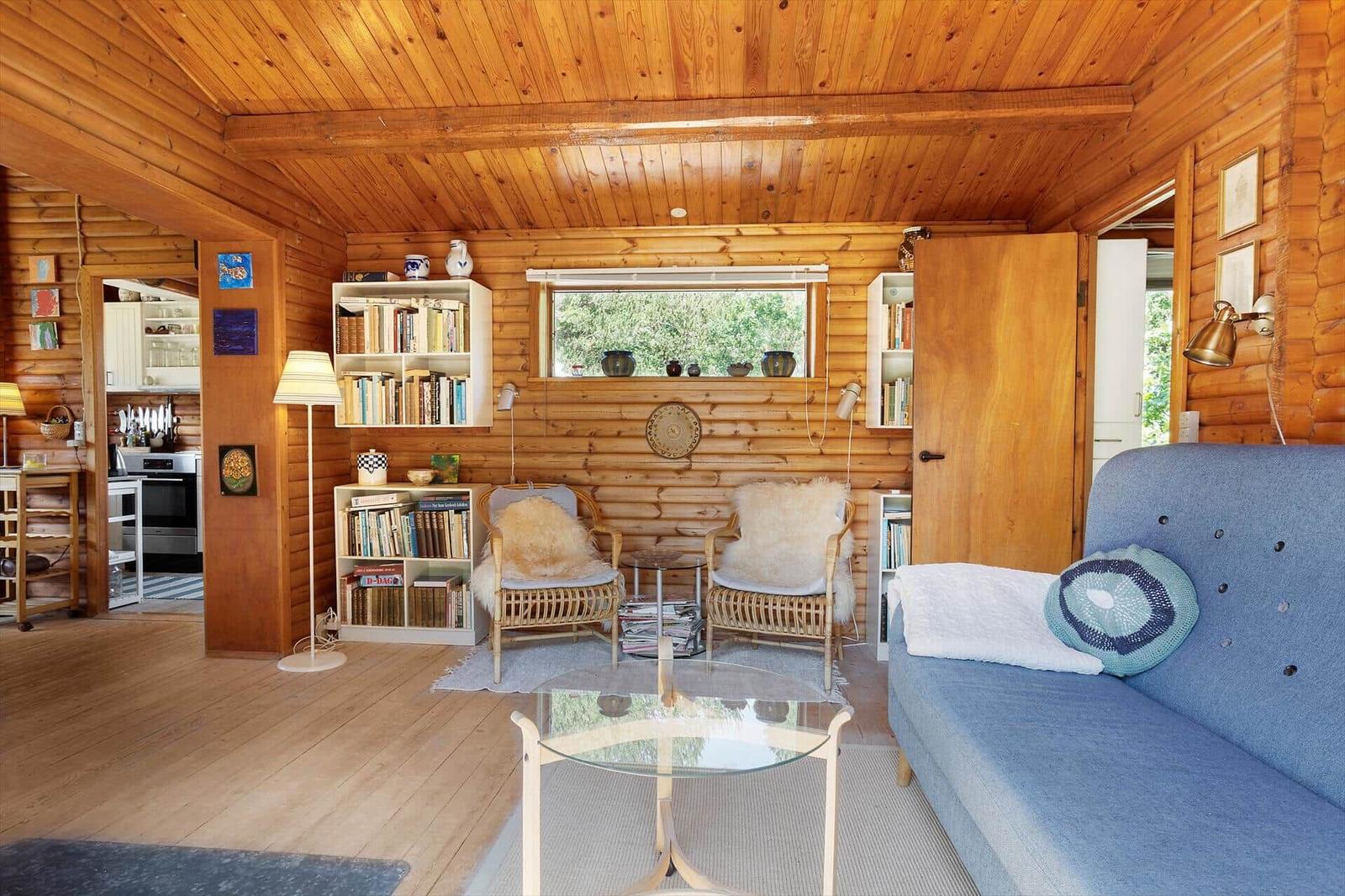 Wohnzimmer mit Holzwand, Sofa, Stühlen und Bücherregalen.