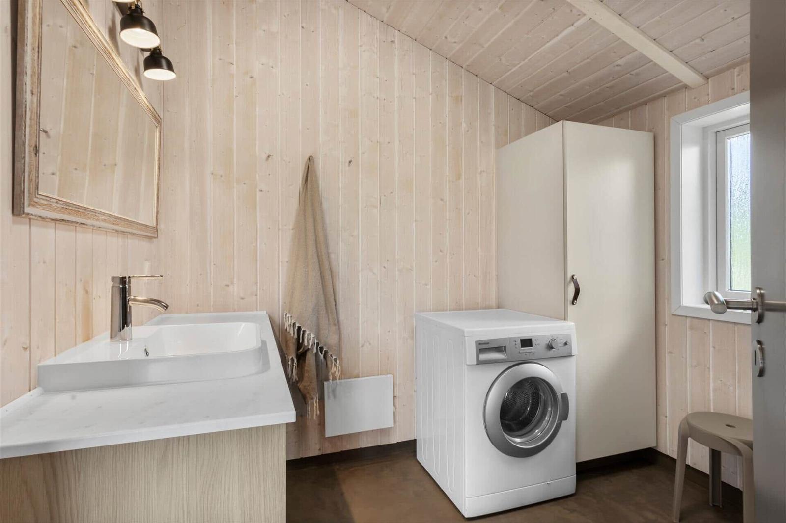Waschraum mit Waschmaschine, Spüle und Spiegelfläche an Holzwand