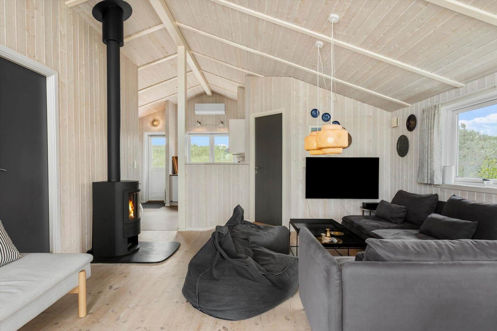 Wohnraum mit Kamin, Sofa und Sitzgelegenheit. Holzwände und Decke.
