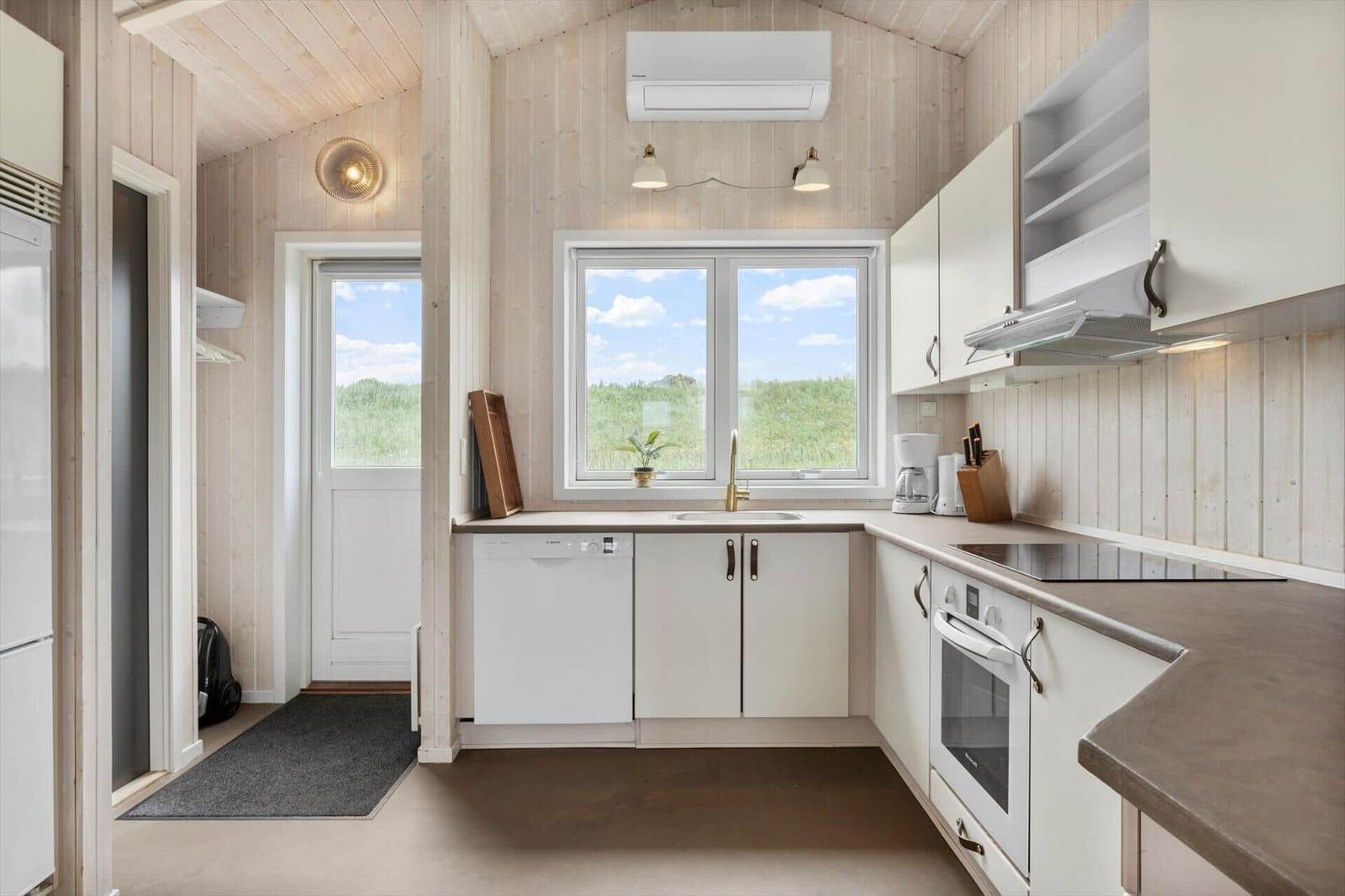 Küche mit weißem Schrank und Fensterblick auf Grasland