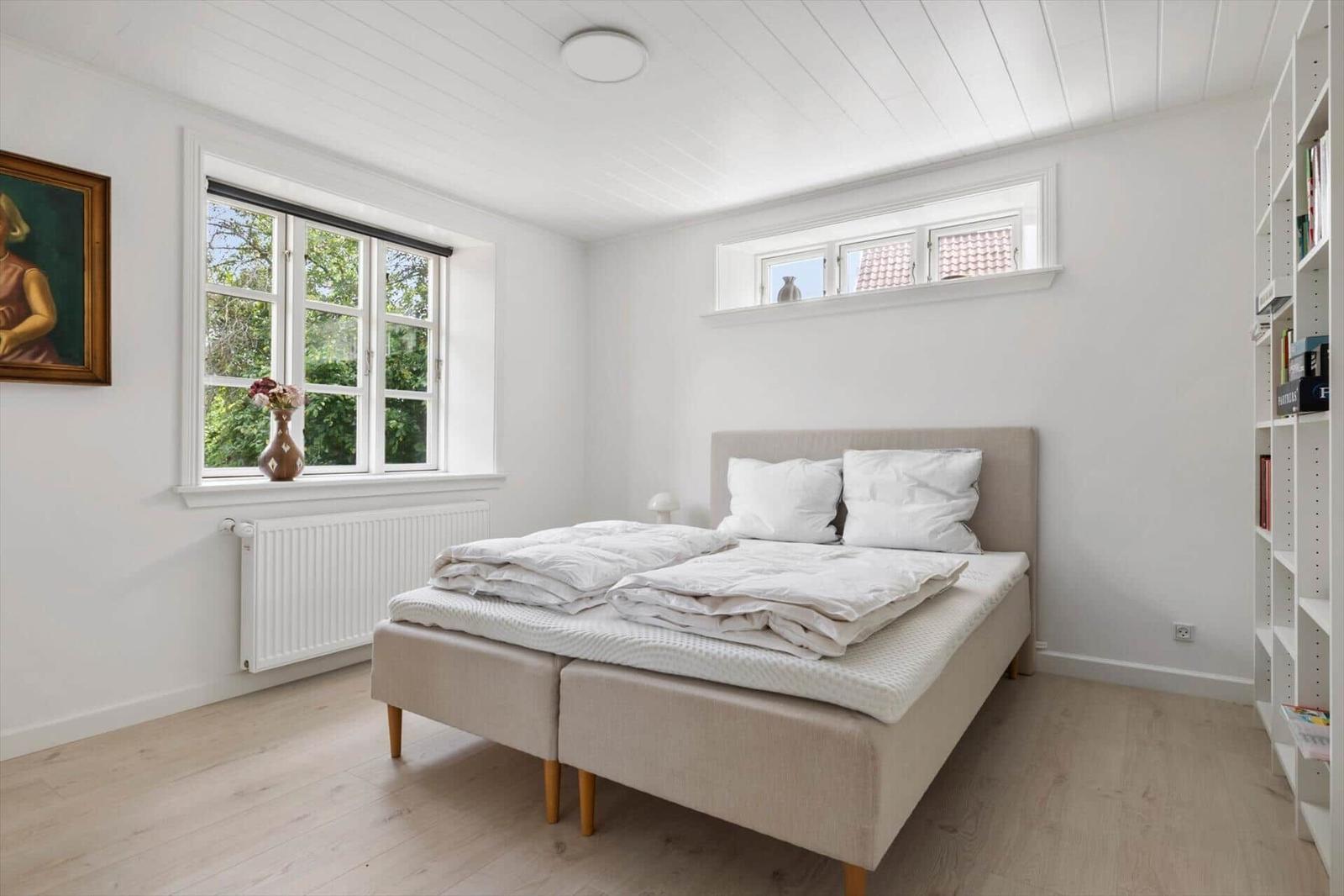 Schlafzimmer mit Bett, Fenster und Bücherregal.
