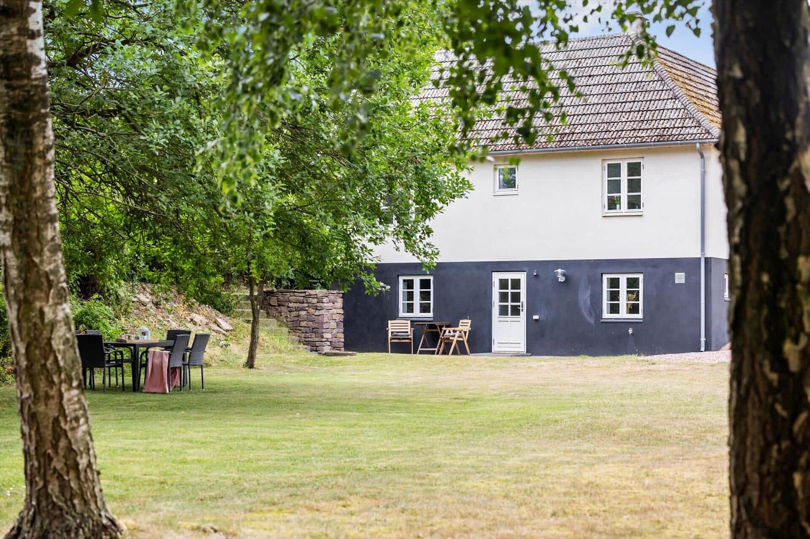 Ein zweistöckiges Haus mit weißem und dunkelblauem Anstrich, umgeben von Gras und Bäumen.