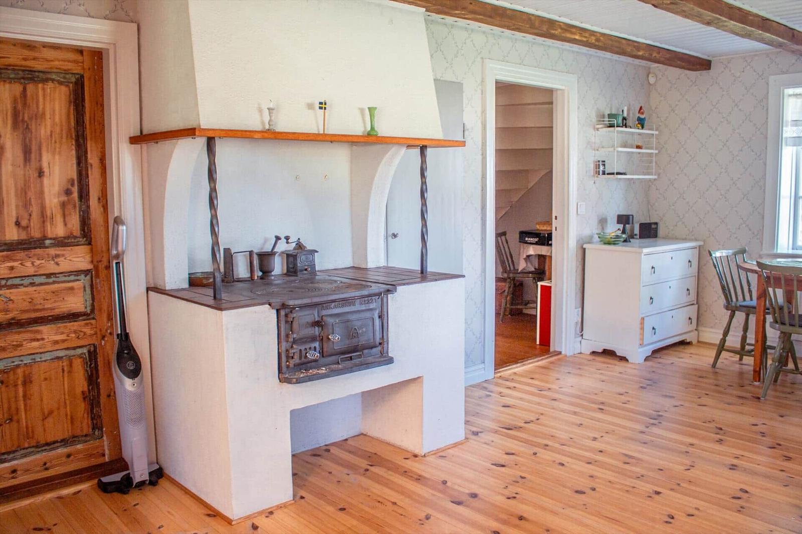 Küche mit altem Ofen, Holzboden und Treppe im Hintergrund.