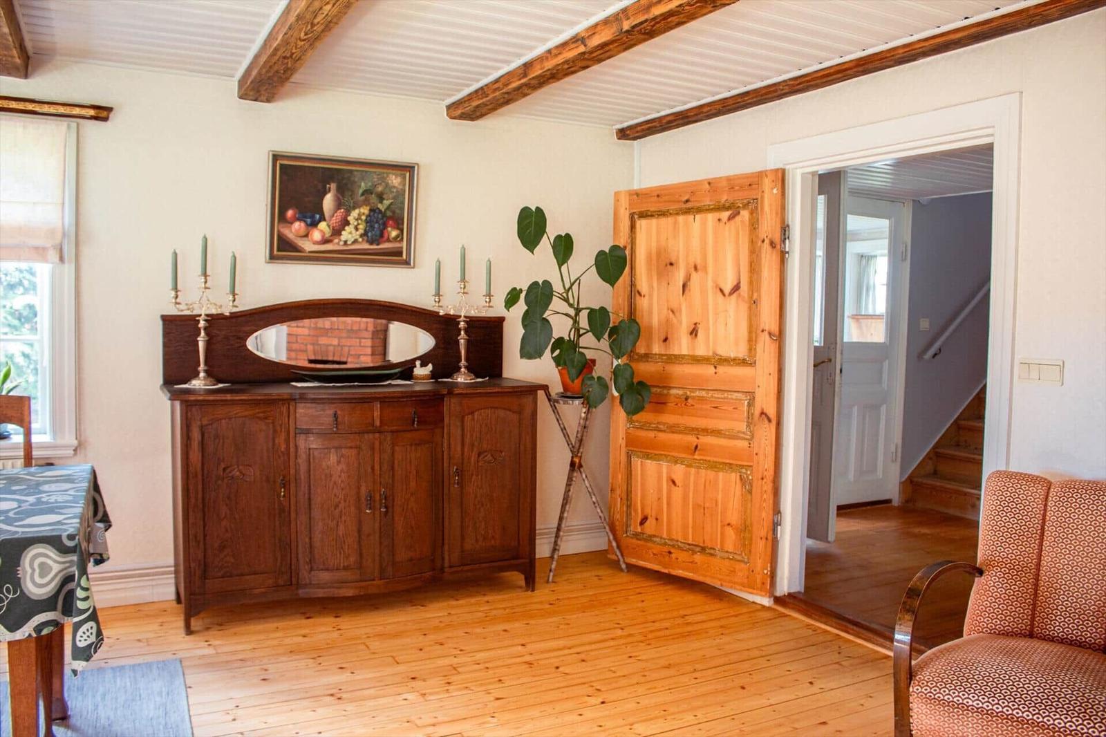 Ein Raum mit Holzboden, einem Holzschrank, einer Pflanze und einer Tür.