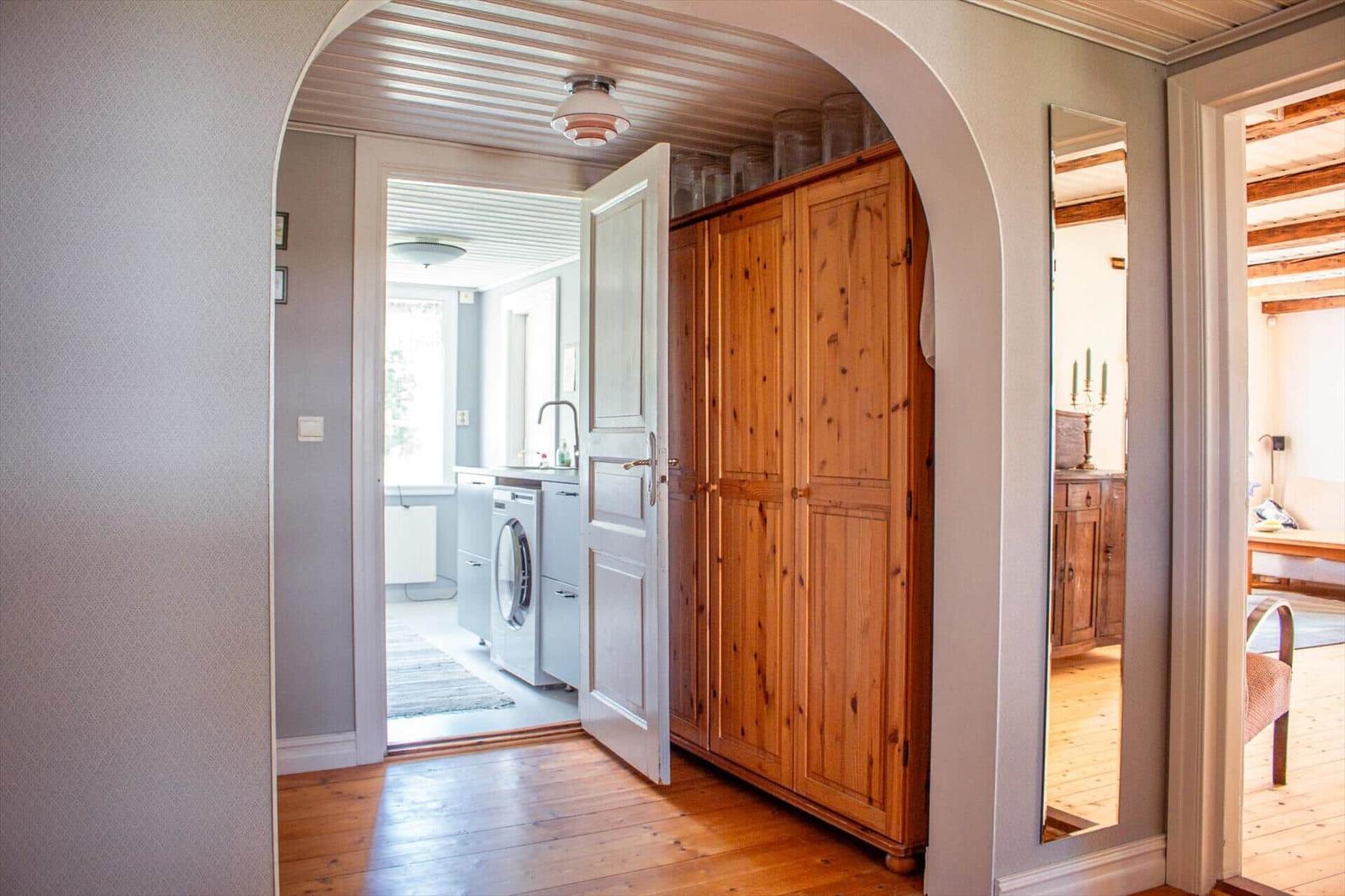 Hausgang mit Holzschrank, Spiegel und Blick in Waschraum und Schlafzimmer