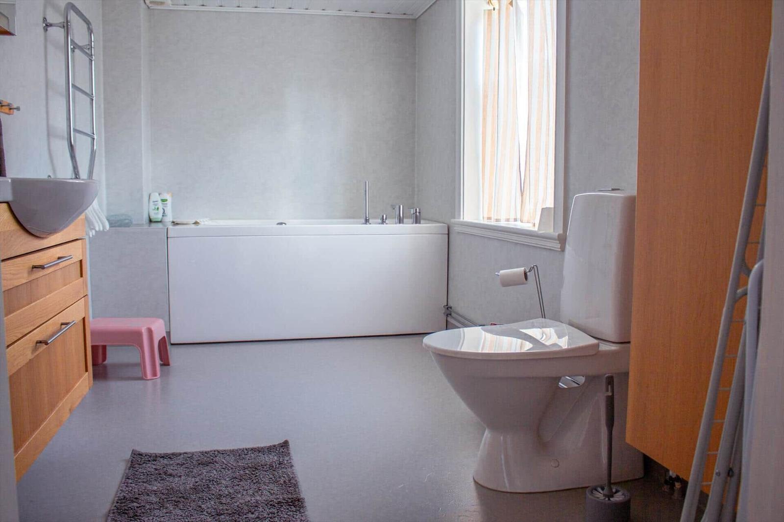 Badezimmer mit Badewanne, Toilette und Waschbecken mit Holzschrank.