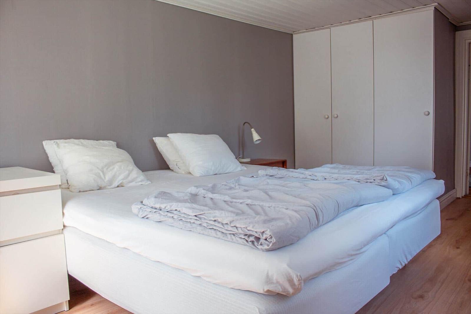 Schlafzimmer mit Doppelbett, weißen Kissen und Kleiderschrank.