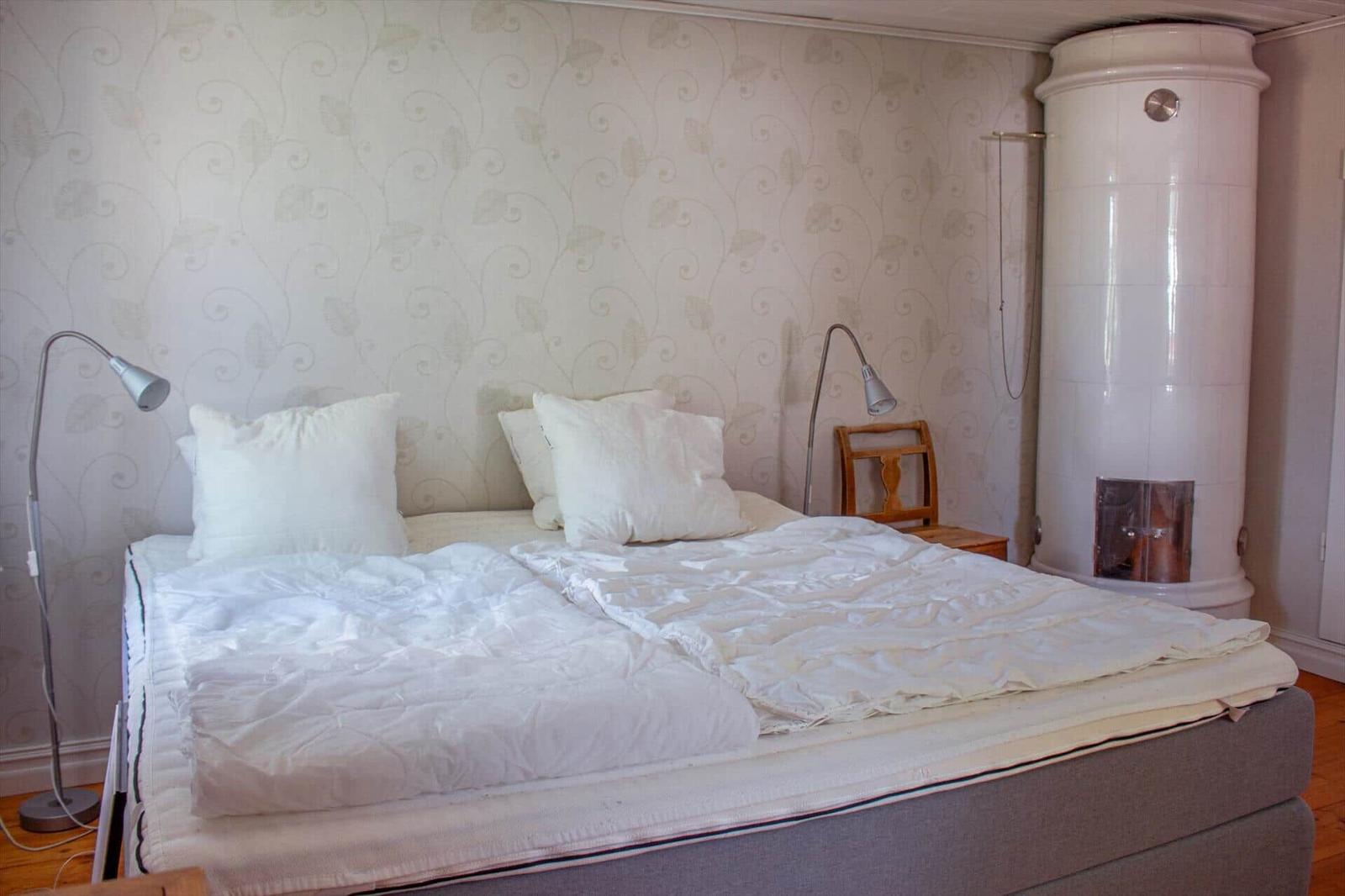Schlafzimmer mit Bett, Stehlampe und weißer Zentralheizung.