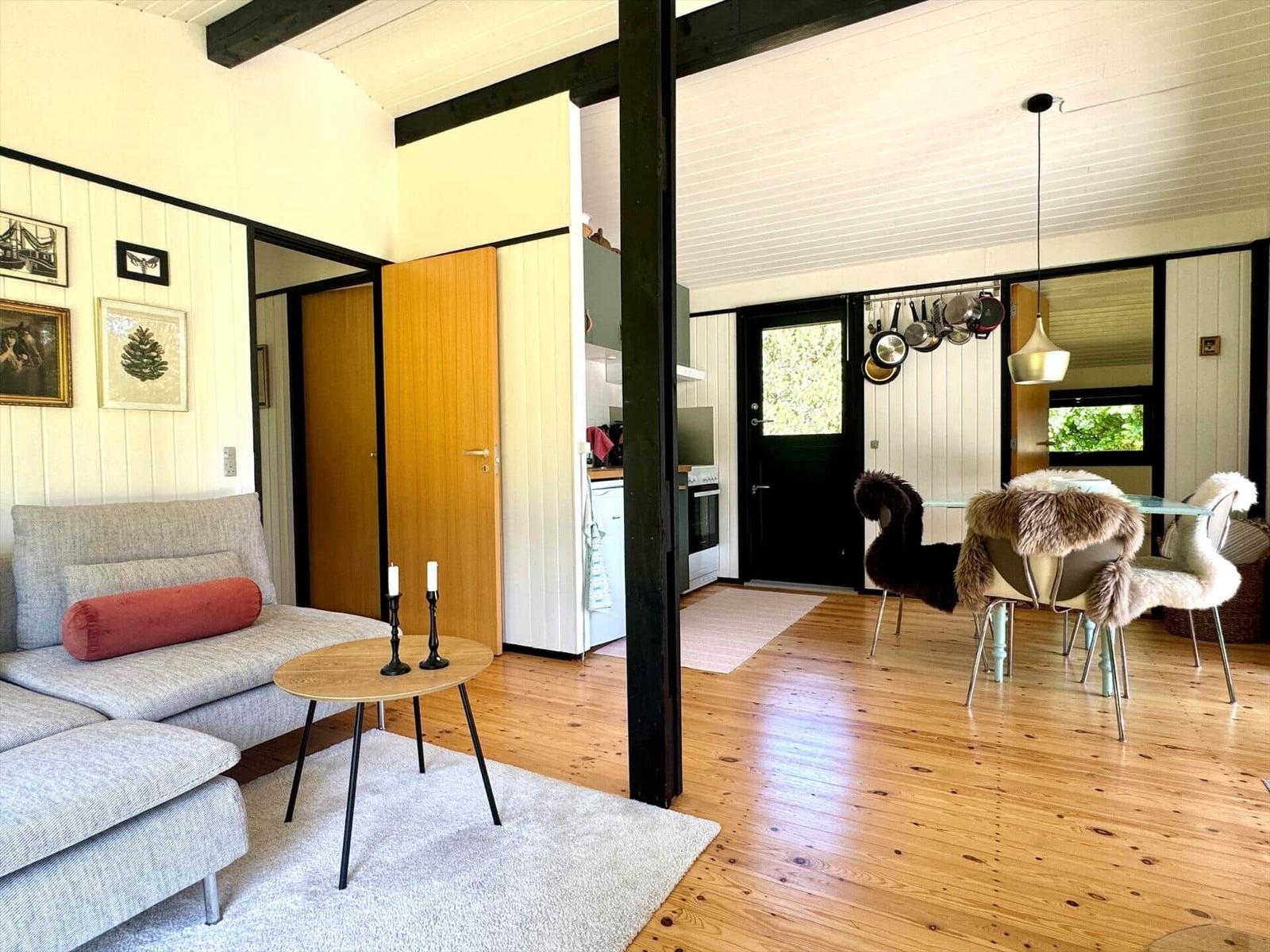 Wohn- und Essbereich mit Holzboden, Sofa, Tisch und Stühlen mit Fellbezügen.